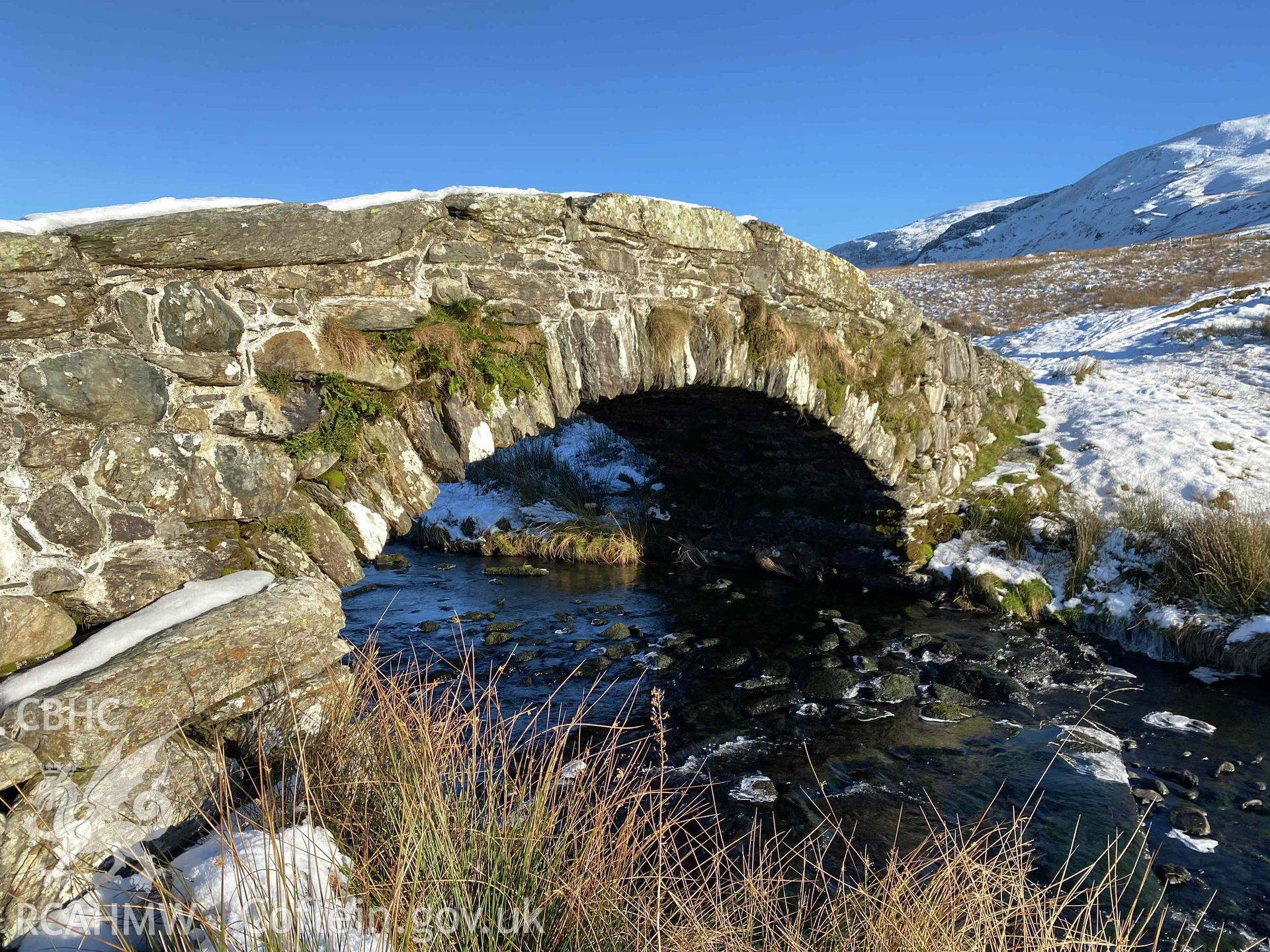 Digital photograph of Pont Scethin Packhorse Bridge in snow, produced by Paul Davis in 2023