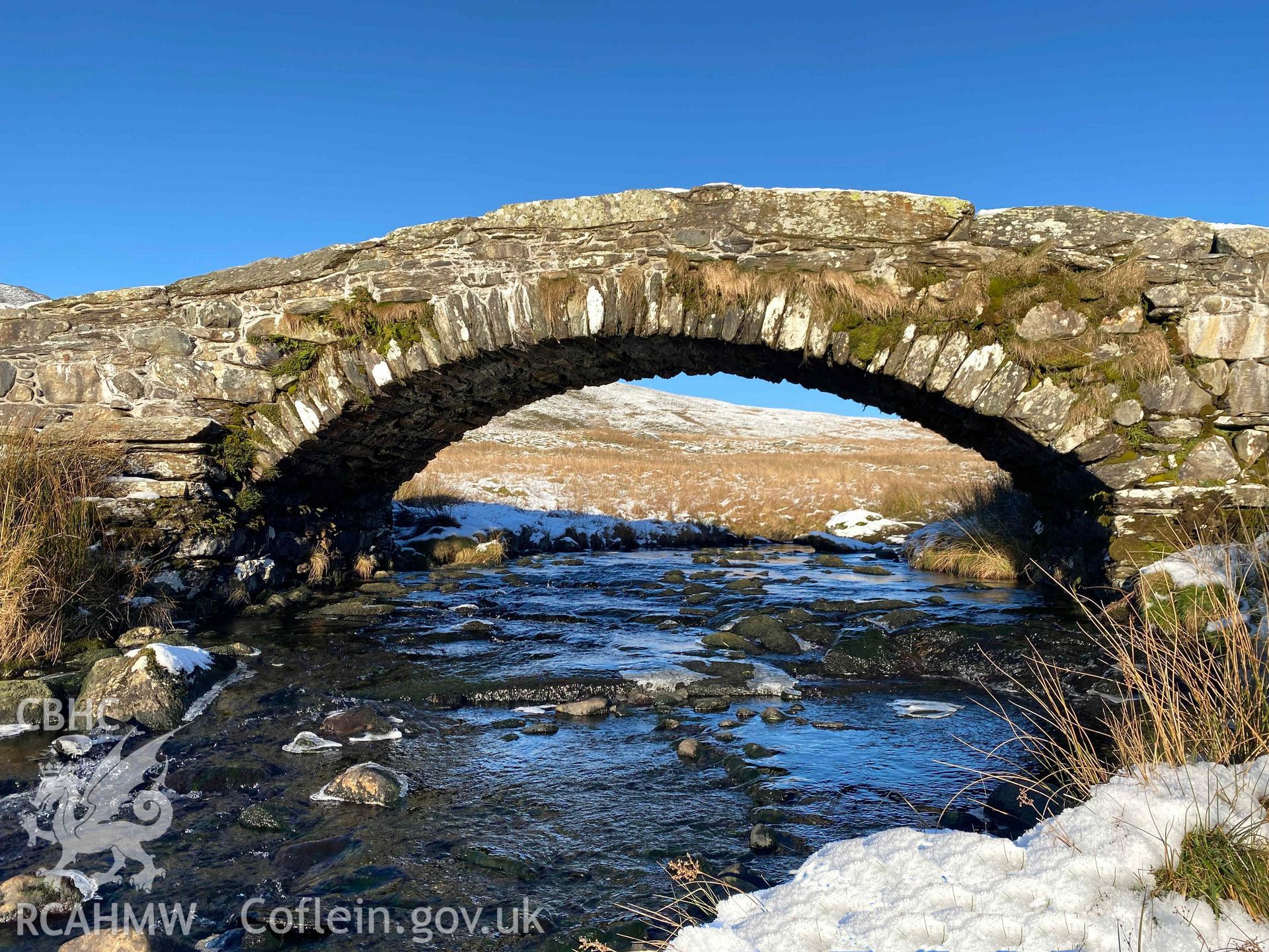 Digital photograph of Pont Scethin Packhorse Bridge in snow, produced by Paul Davis in 2023