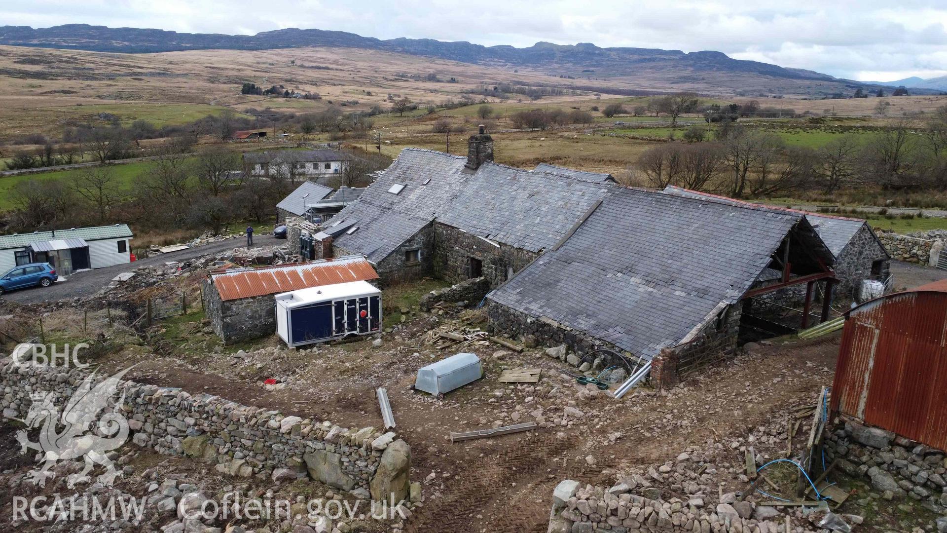 Aerial view of Tyddyn Mawr farmhouse and outbuildings looking northwest towards the Rhinogydd. Part of a photographic survey of Tyddyn Mawr farmhouse, Trawsfynydd, conducted by Dr Jayne Kamintzis of RCAHMW on 13 June 2023.