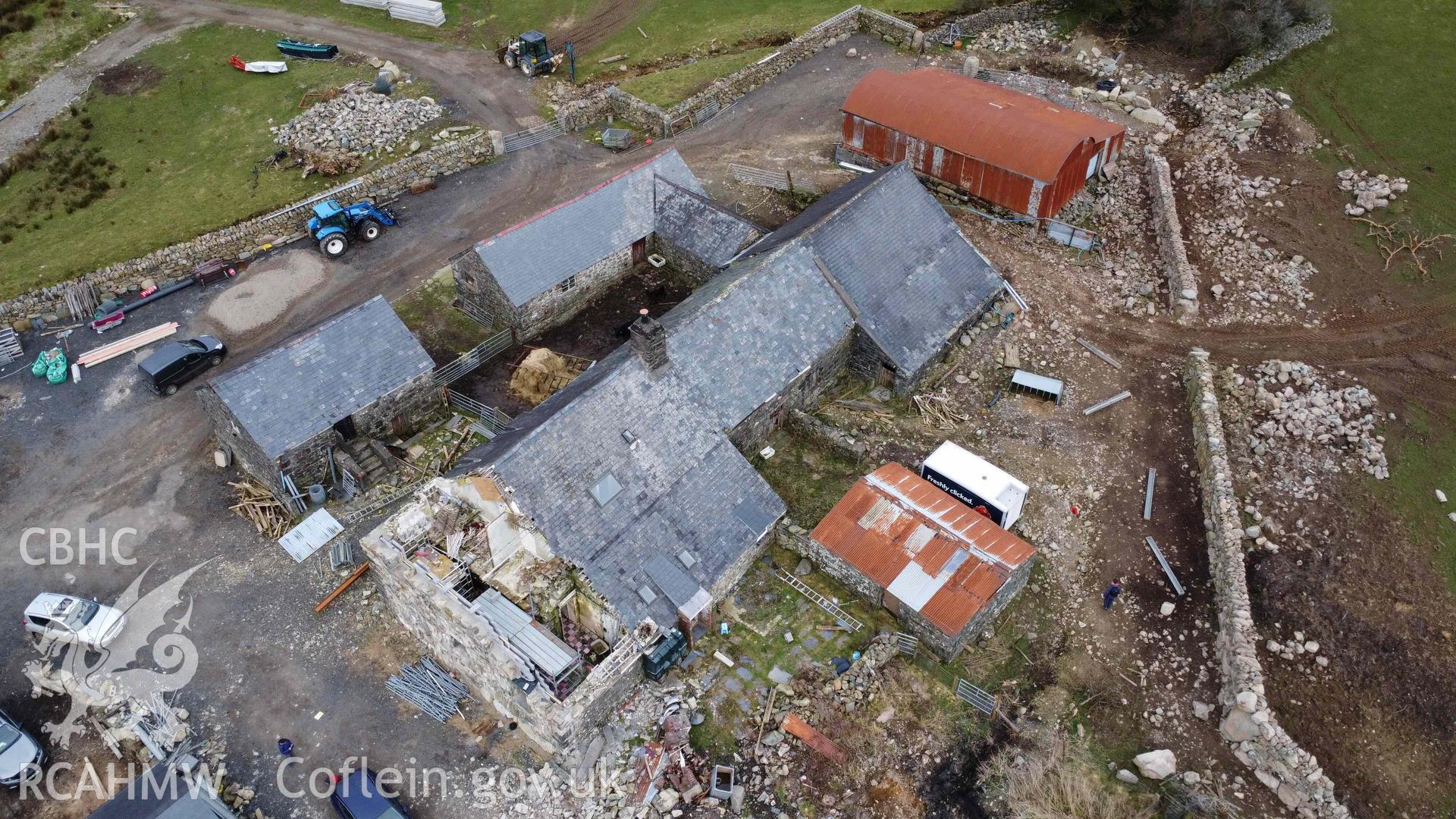 Aerial view of Tyddyn Mawr farmhouse and outbuildings showing the boarded up western gable end of the house and the 2023 rebuilding. Part of a photographic survey of Tyddyn Mawr farmhouse, Trawsfynydd, conducted by Dr Jayne Kamintzis of RCAHMW on 13 June 2023.