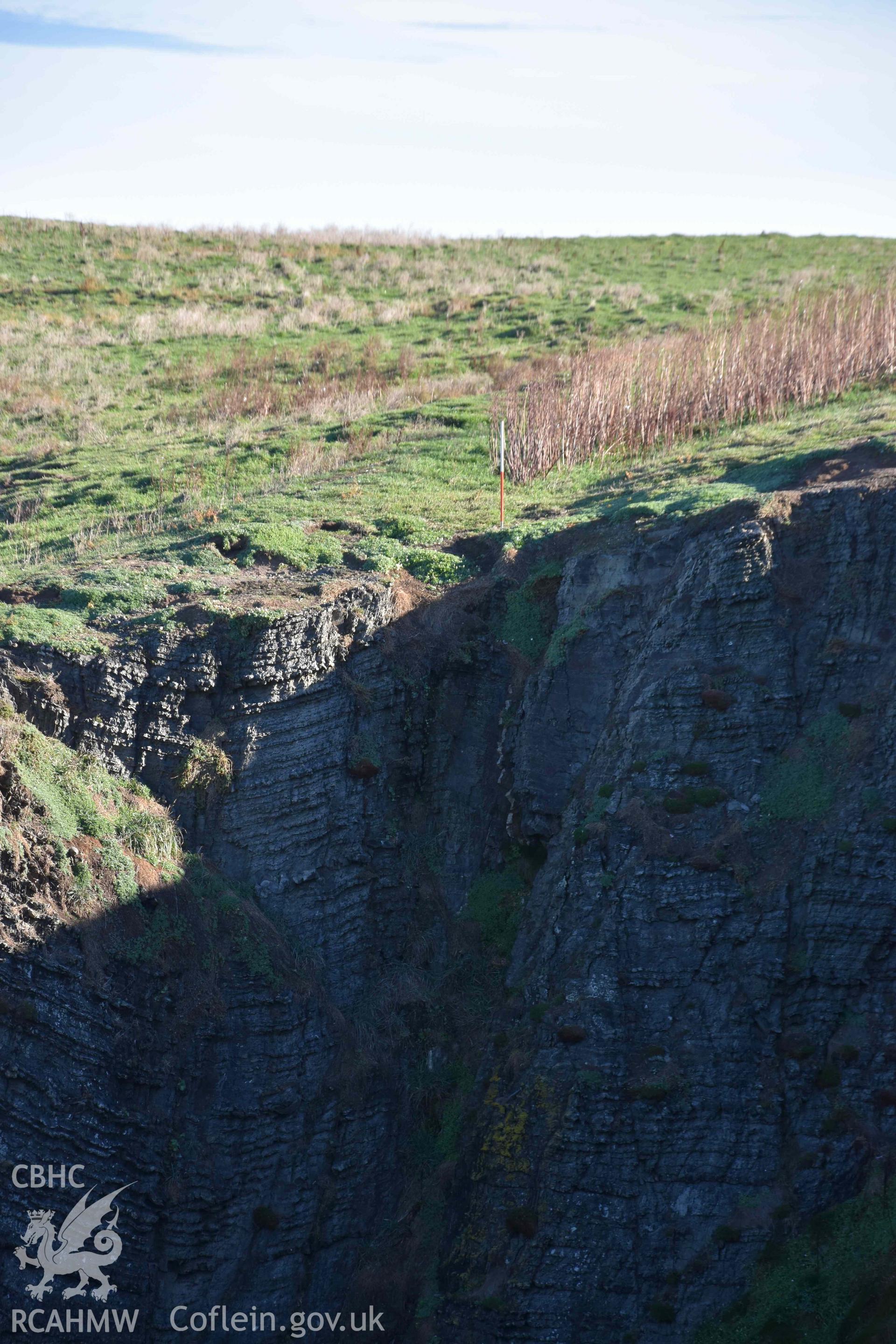 Western end of the promontory enclosure bank at the cliff edge. Part of a digital photographic survey conducted on Cardigan Island by Louise Barker of RCAHMW on 30 October 2018. Produced with EU funds through the Ireland Wales Co-operation Programme 2014-2023. All material made freely available through the Open Government Licence.