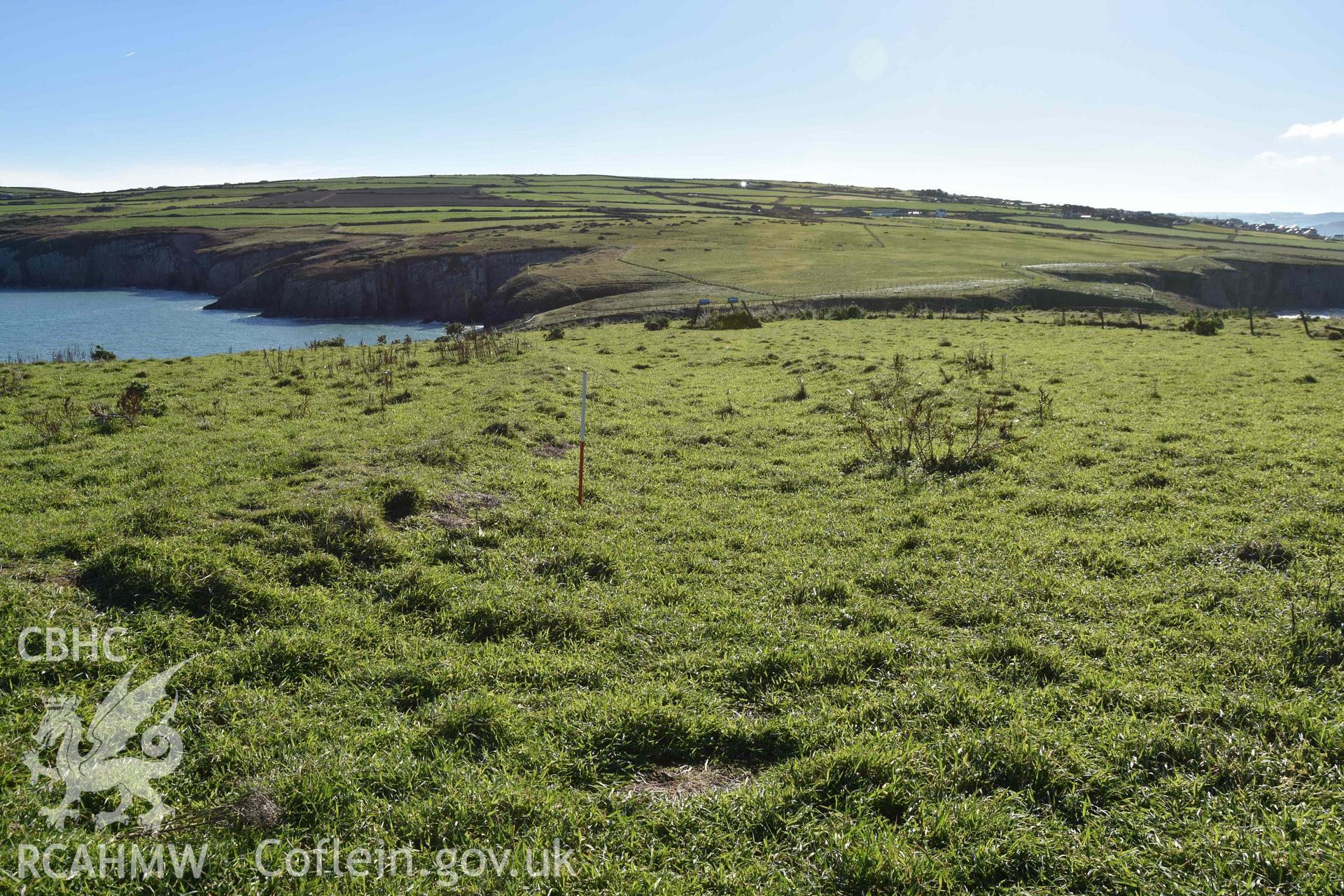 View looking southeast along bank defining the western side of the settlement enclosure on Cardigan Island, with small annexe to the right. Part of digital photographic survey conducted by Louise Barker of RCAHMW on 30 October 2018. Produced with EU funds through the Ireland Wales Co-operation Programme 2014-2023. All material made freely available through the Open Government Licence.