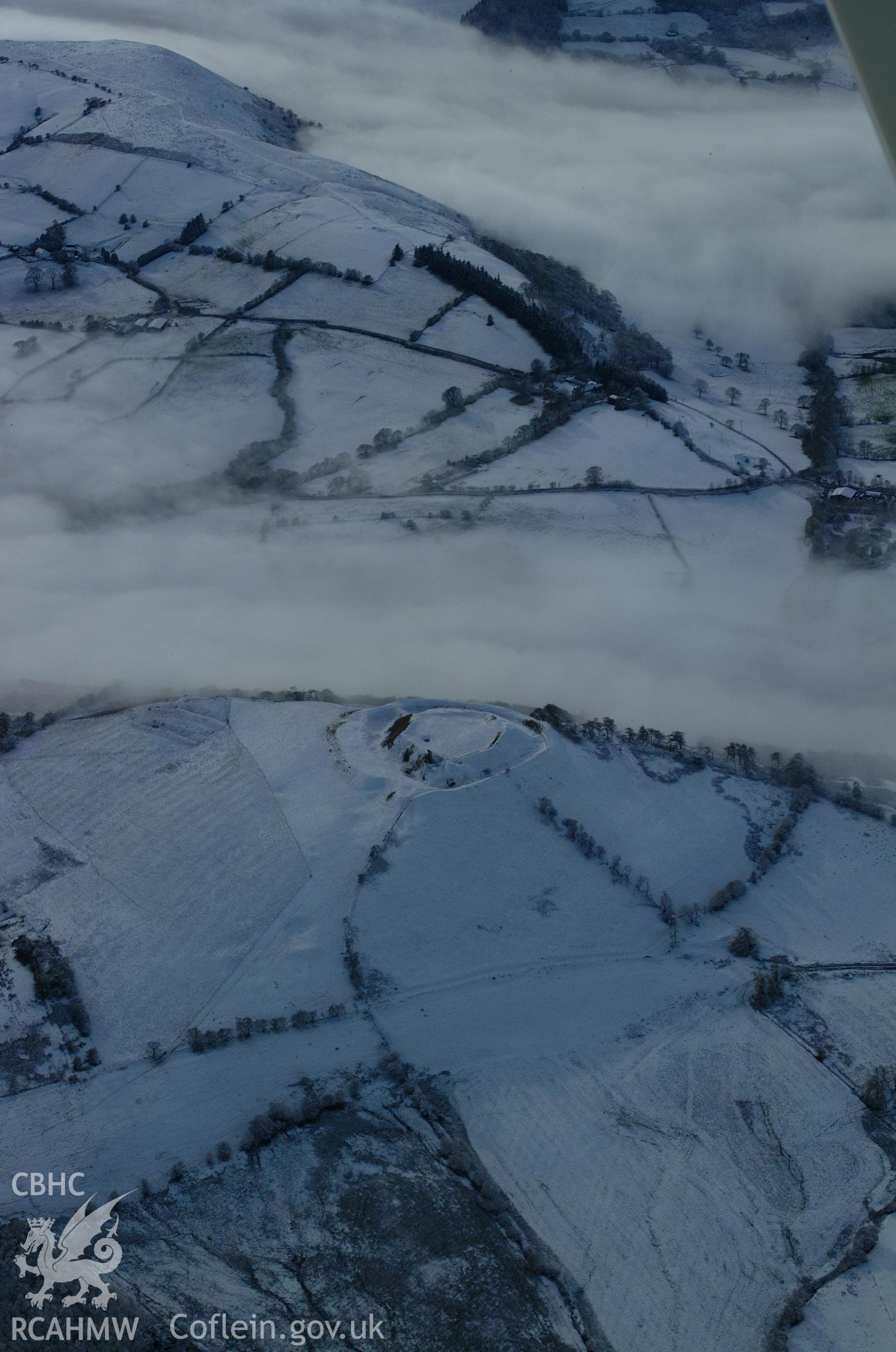 RCAHMW colour oblique aerial photograph of Castell Tinboeth, Llananno. A view from the north-east showing the site under snow with freezing fog in the valleys. Taken on 19 November 2004 by Toby Driver