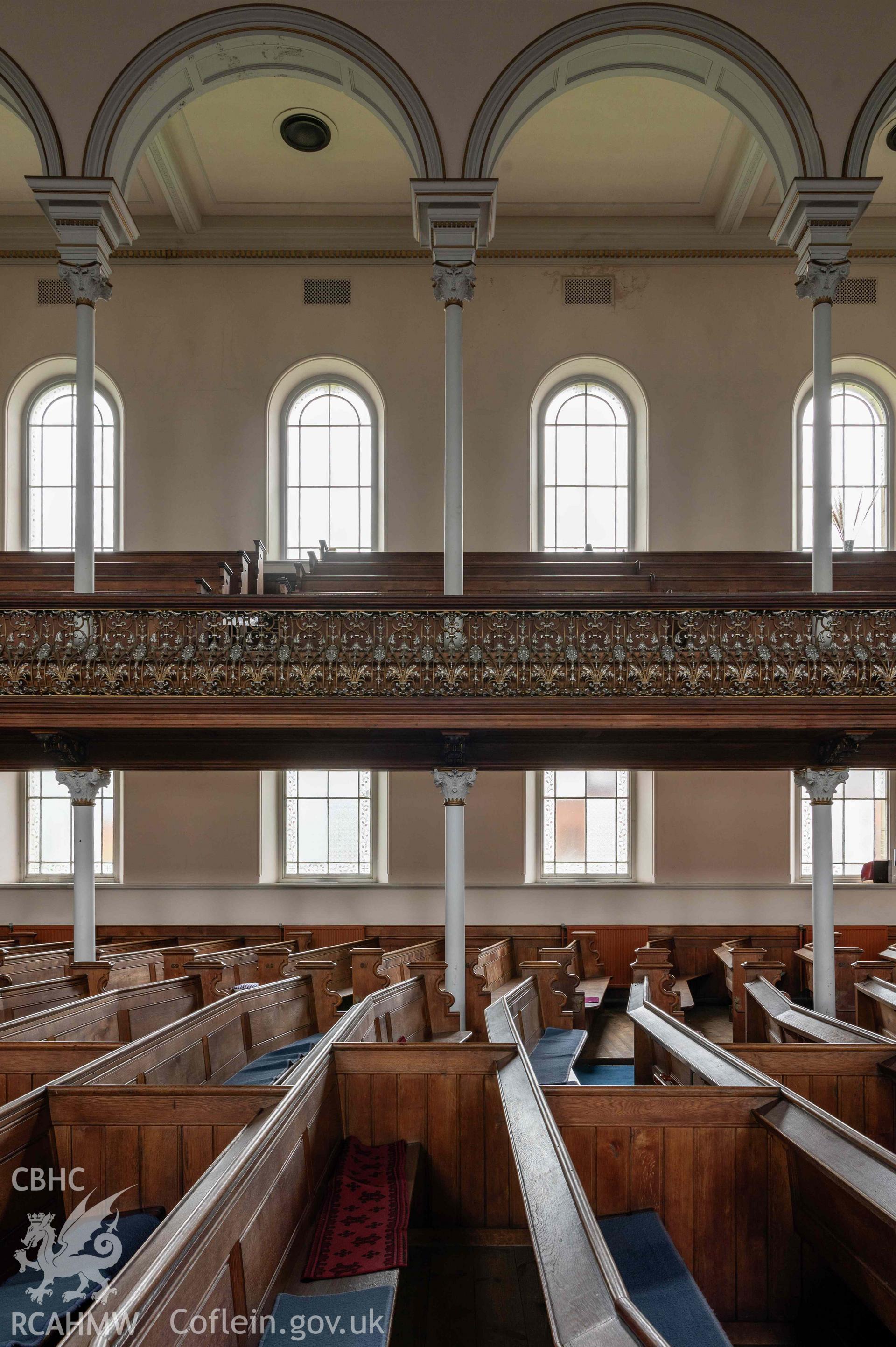 Capel Zion Baptist Chapel, Newtown - auditorium, looking south-west ground floor, ground floor pews, raked gallery pews, gallery front and gallery columns.