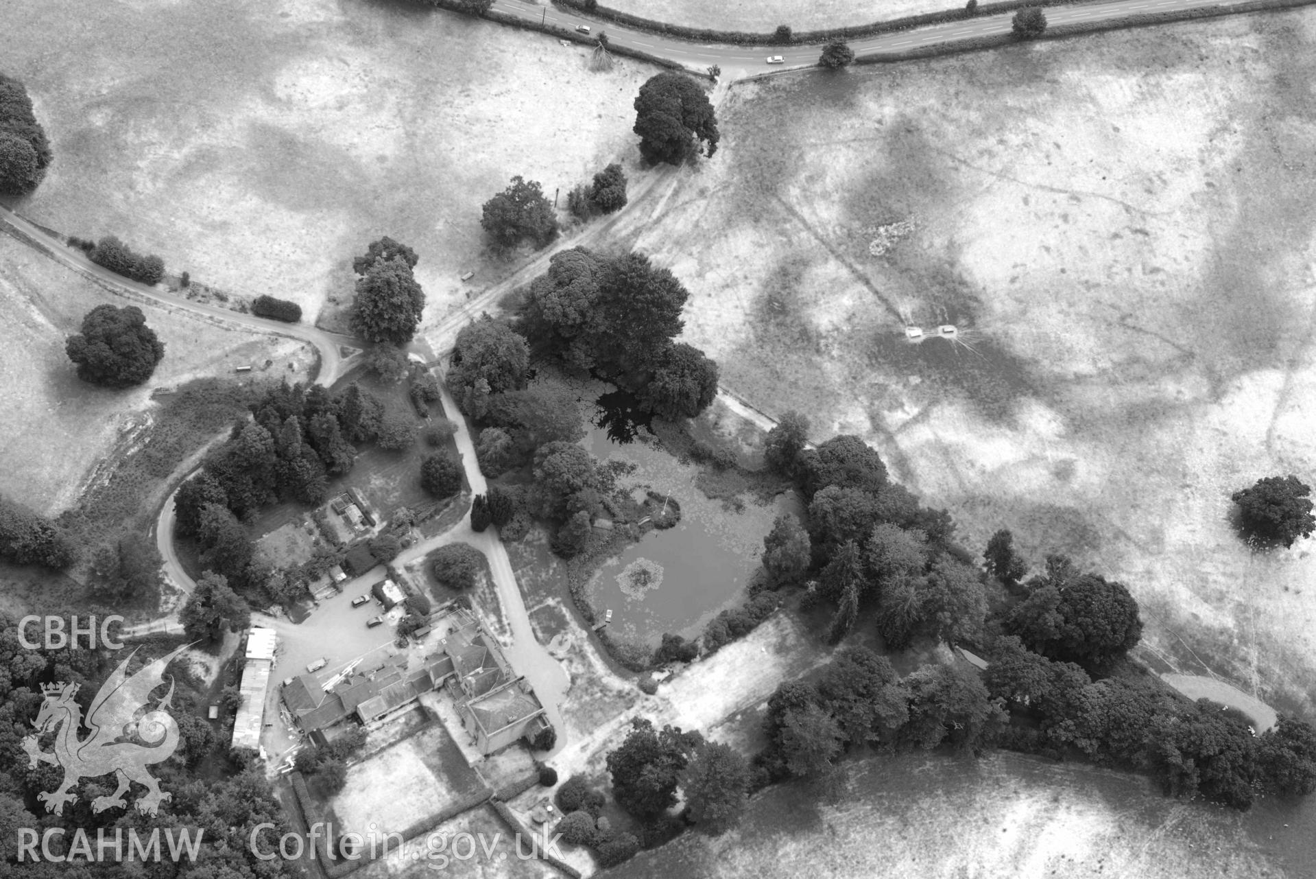 Cropmarks at Tower Garden, Mold. Oblique black and white aerial photograph taken during the Royal Commission’s programme of archaeological aerial reconnaissance by Toby Driver on 10 July 2018.