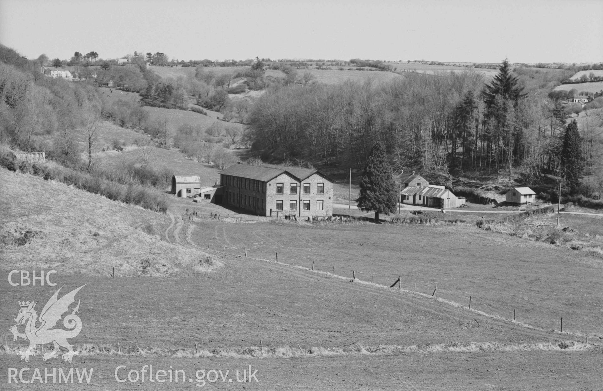 Digital copy of a black and white negative showing the woollen factory at Maesllyn, Llangynllo, with drying frame on extreme left. Photographed by Arthur Chater on 5 April 1969. Looking north east from Grid Reference SN 3663 4469.