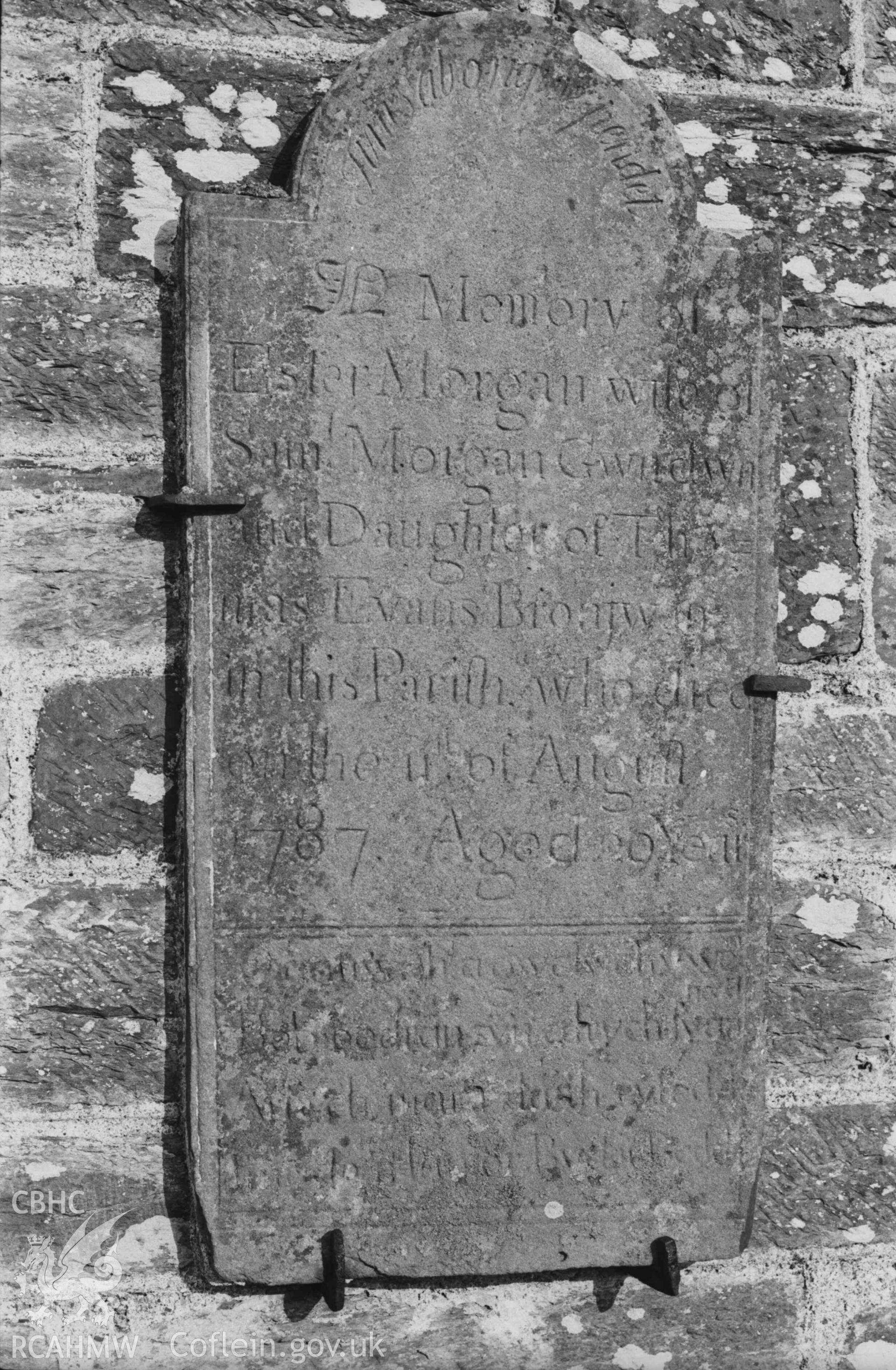 Digital copy of a black and white negative showing tombstone mounted against the east wall of Troedyraur church. Photographed by Arthur Chater on 5 April 1969.  Looking east from Grid Reference SN 3270 4537.