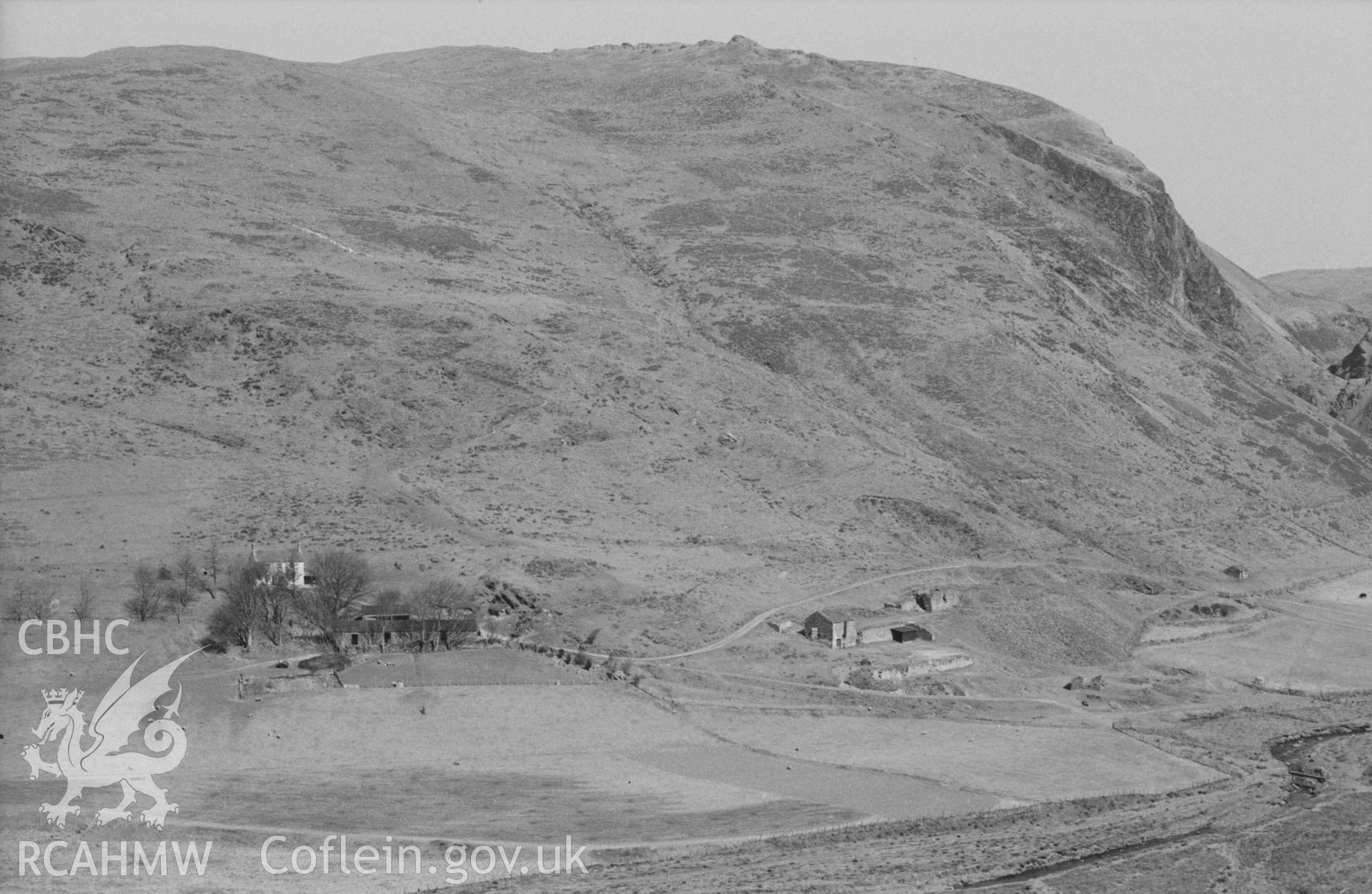 Digital copy of a black and white negative showing Llawr-y-Cwm-bach farm and mine (right). Photographed by Arthur Chater on 6 April 1969. Looking east north east from Grid Reference SN 701 853.