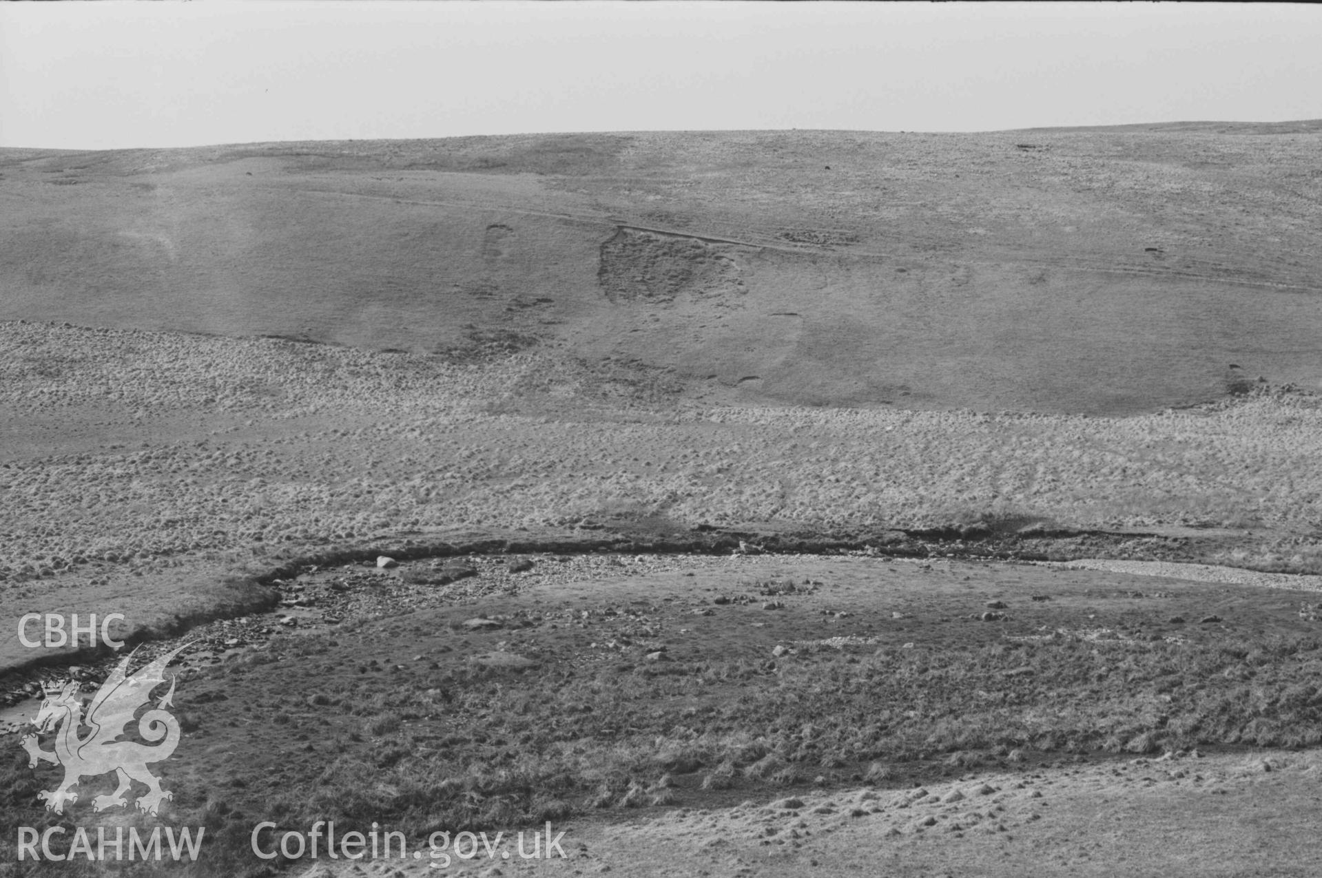 Digital copy of a black and white negative showing view across the Afon Claerwen to Esgair Hengae, showing old road sloping down from left to right, ruins of Hengae (just right of centre) and Rhyd Hengae (extreme right). Panoramic view, photo 1 of 3. Photographed by Arthur Chater on 8 April 1969. Grid Reference SN 8220 6780.