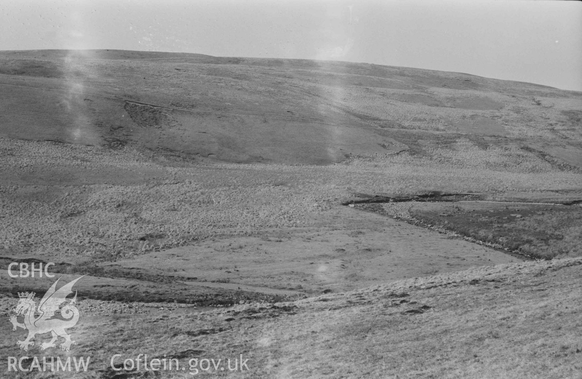 Digital copy of a black and white negative showing view across the Afon Claerwen to Esgair Hengae, showing old road and ruin of Hengae (right). Photographed by Arthur Chater on 8 April 1969. Looking north west from Grid Reference SN 8215 6768.