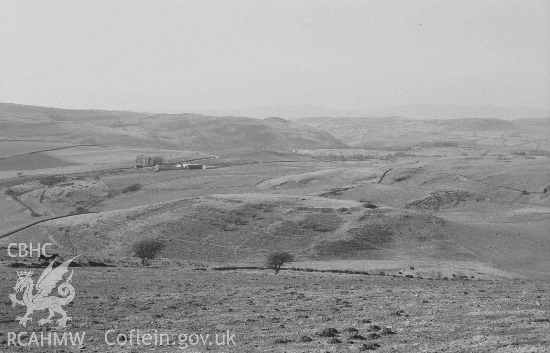 Digital copy of a black and white negative showing view from the road 60m east of Tan-y-Bryn (Upper) to Pen-y-Castell and Pendinas iron-age camps (both in line in centre). Photographed by Arthur Chater on 6 April 1969. Looking north north west from Grid Reference SN 6918 8430.