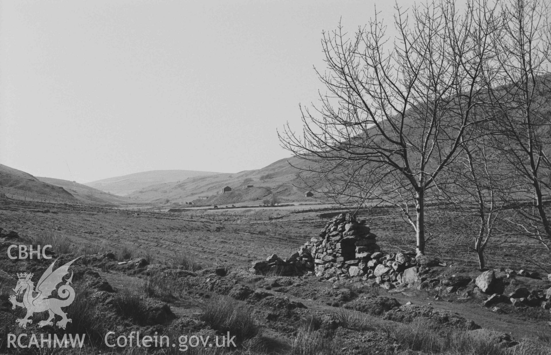 Digital copy of a black and white negative showing ruin 200m south south east of Llawr-y-cwm-mawr; Llawr-y-cwm-bach lead mine down valley in distance. Photographed by Arthur Chater on 6 April 1969. Looking west north west from Grid Reference SN 7129 8514.