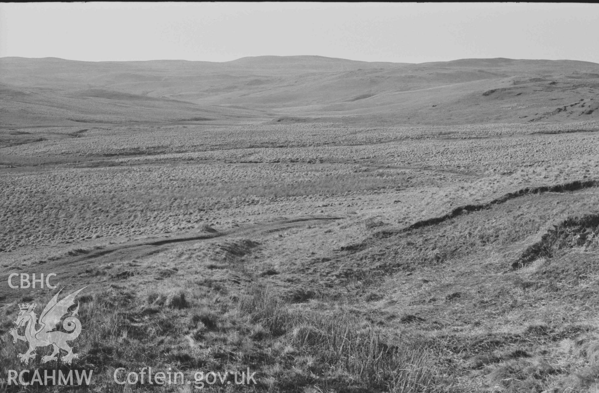 Digital copy of a black and white negative showing the old road joining the new road (left) to Claerwen; looking up the Afon Claerddu to Trawssallt. Photographed by Arthur Chater on 8 April 1969. Looking north west from Grid Reference SN 8085 6760.