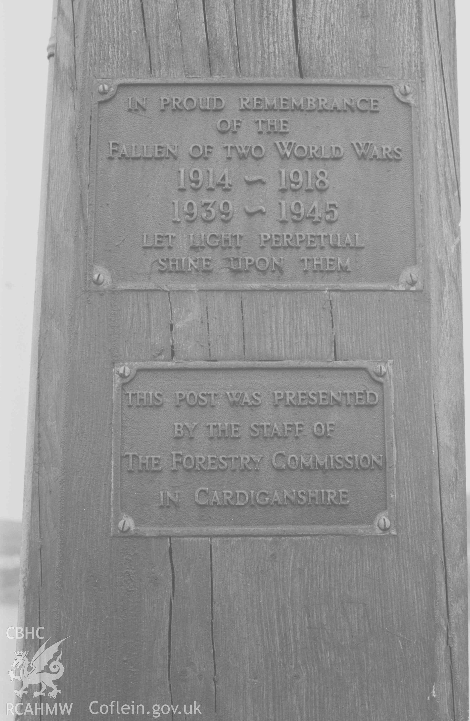 Digital copy of a black and white negative showing plaques on oak light-post at the end of the Pier, New Quay. Photographed by Arthur Chater on 9 April 1969. Looking east from Grid Reference SN 3925 6015.
