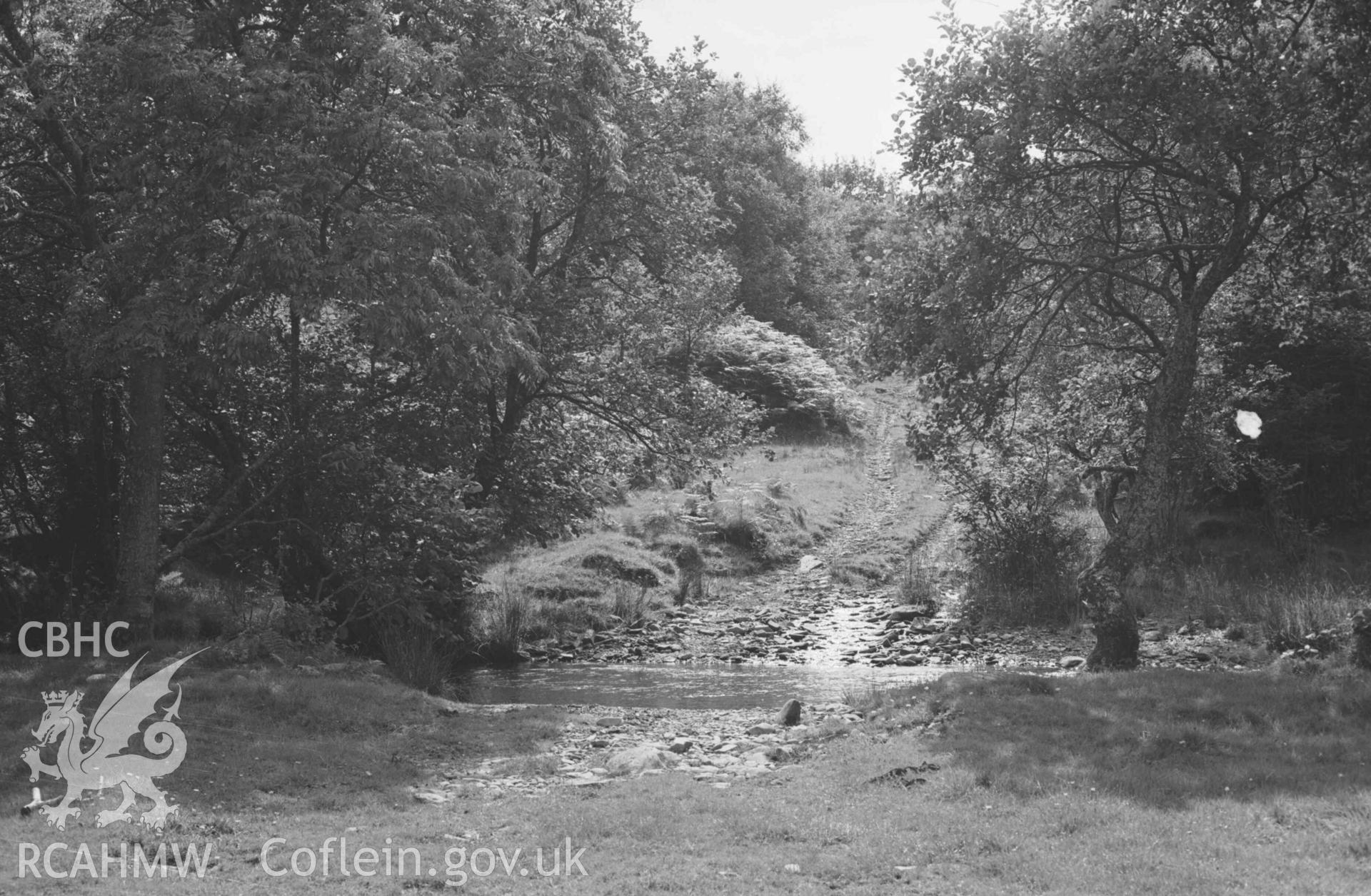 Digital copy of a black and white negative showing the ford over the Glasffrwd, on the track from Strata Florida to Talwrn - looking into Coed Cornwall-Fach. Photographed by Arthur Chater on 24 August 1969. Looking south west from Grid Reference SN 7461 6548.