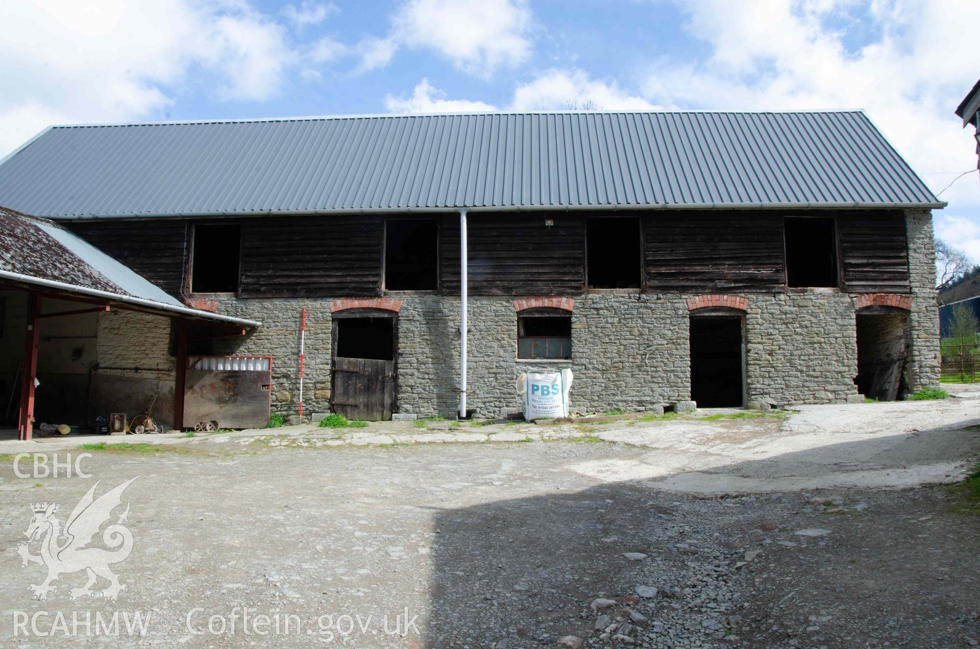 Photograph showing South elevation of cowhouse, showing blocked doors and brick arches over doors. From a Photographic Survey of outbuildings at Upper House Farm Evenjobb, submitted as part of Listed Building consent. Photograph taken by Christopher Welch in April/June 2024.