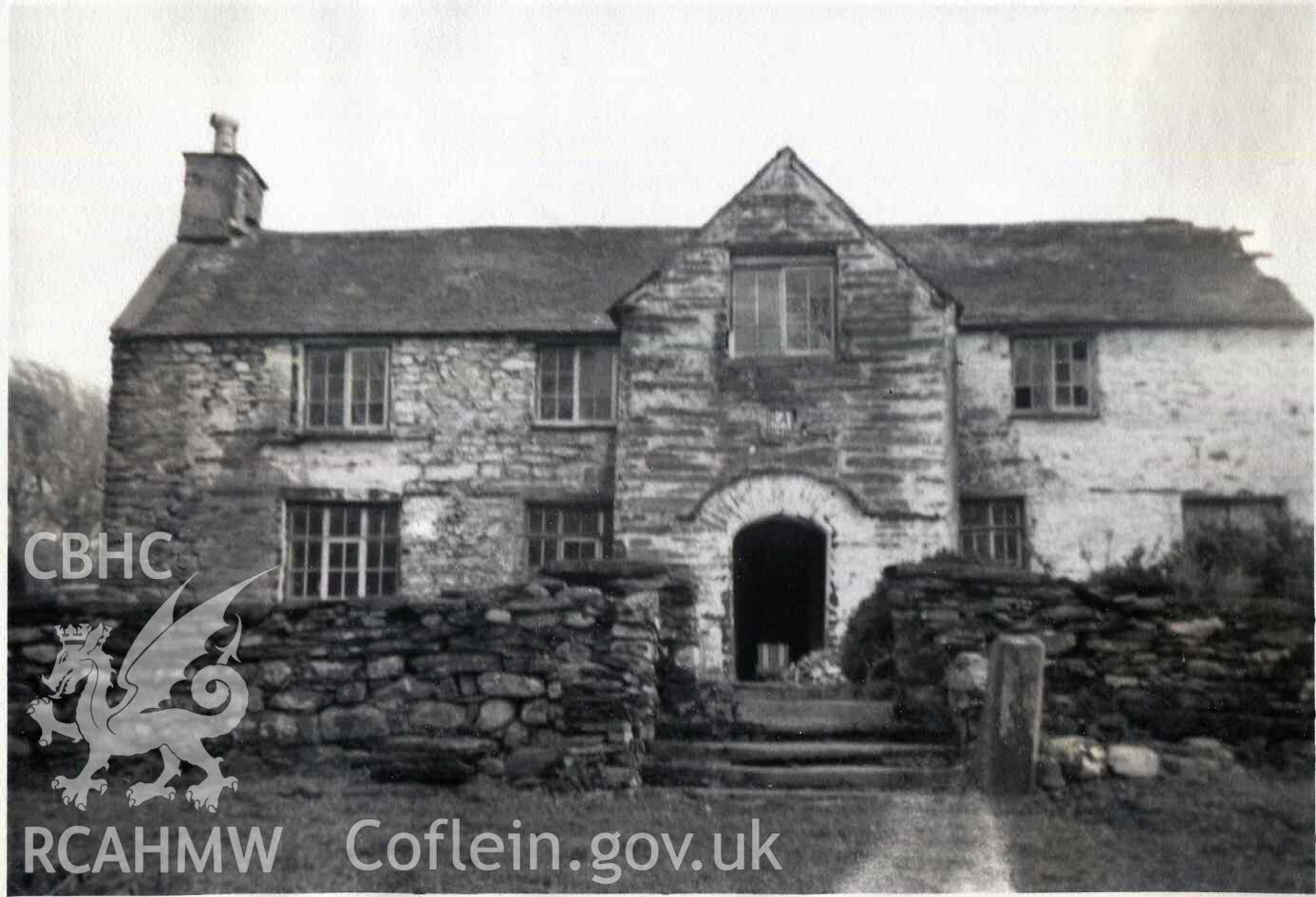 Front elevation of Hafod Dwyryd. The garden has been partly cleared and the house is being opened up. There's a deck chair in the porch. Photographed by Ronald and Joan Adams in about 1963 or 1964.