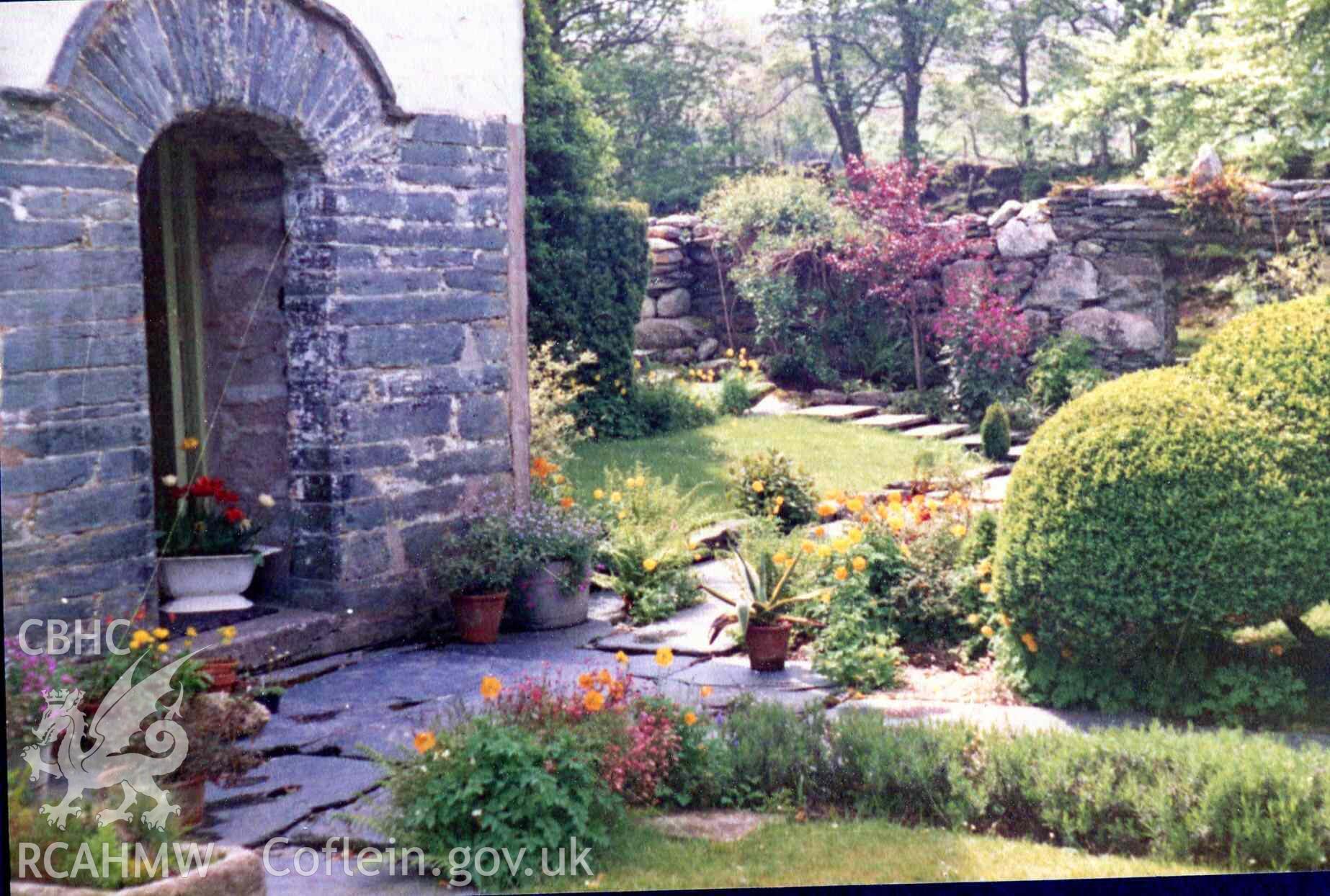 Garden at Hafod Dwyryd with flowers in full bloom. Front door painted green. Photographed by Ronald and Joan Adams in the late 1970s.