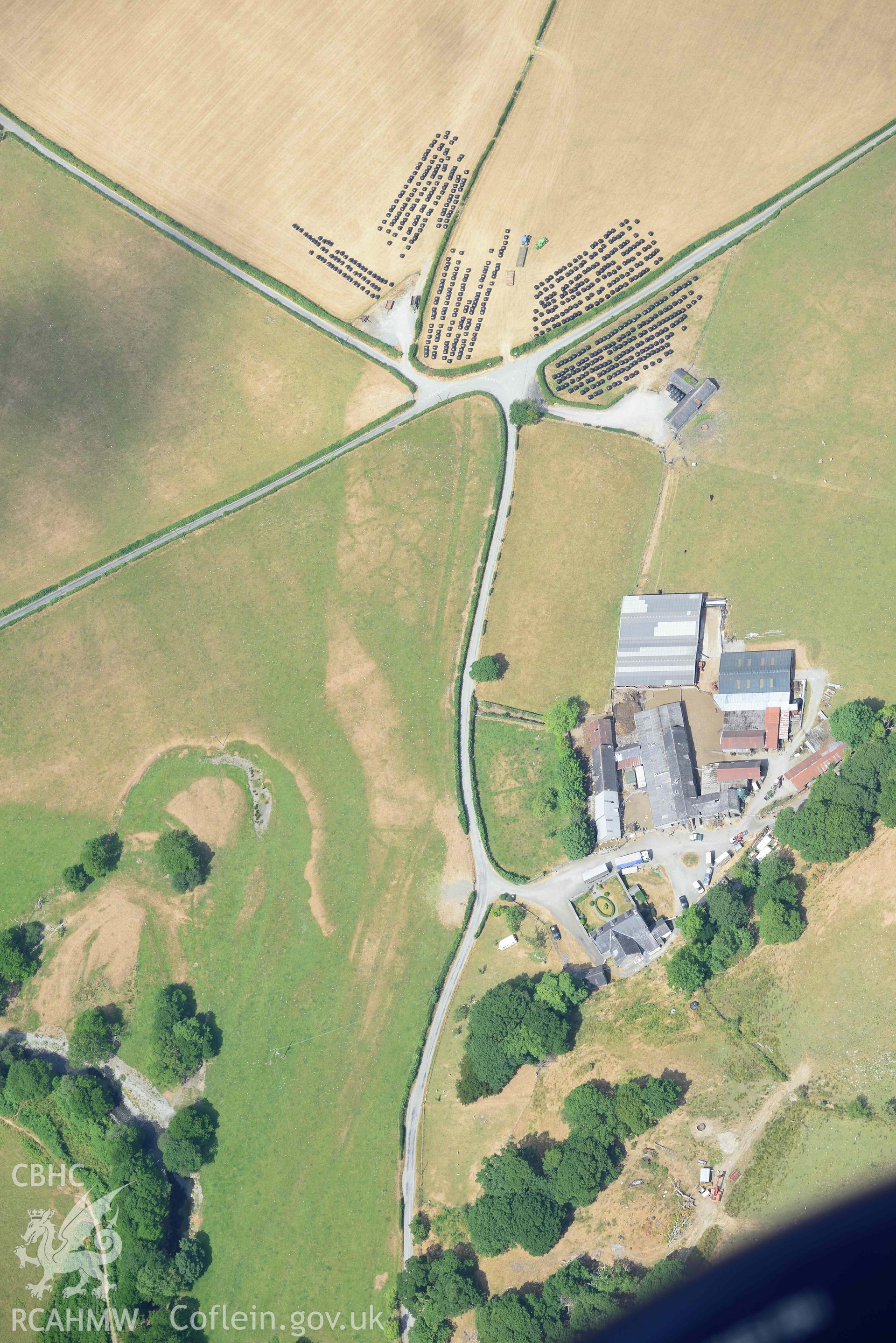 Caer Berllan farm and ditch, with silage bales. Oblique aerial photograph taken during the Royal Commission’s programme of archaeological aerial reconnaissance by Toby Driver on 10 July 2018.