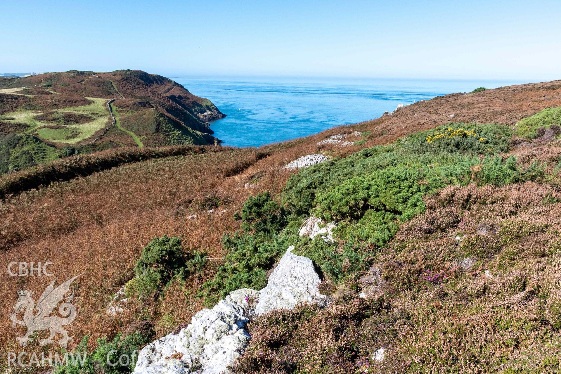 Dinas Gynfor Coastal Hillfort. View from rock outcrops in hillfort interior looking southwest, with a shadow cast along a second line of defenses defining an enclosure against the rock outcrops.