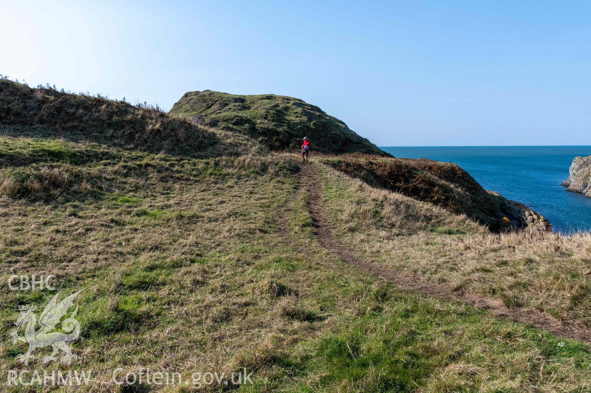 Twyn y Parc Coastal Promontory Fort. Looking south to inner gateway (with person) overlooking Porth Fain at northwest terminal of inner rampart.