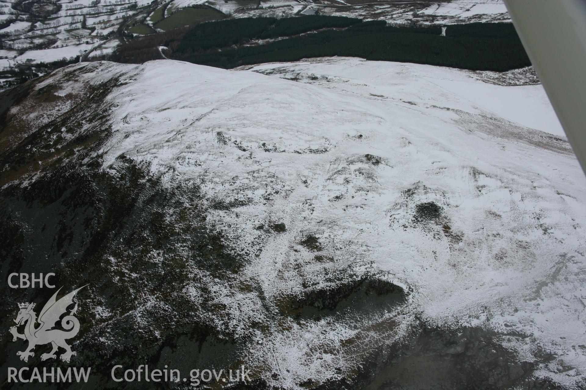 RCAHMW colour oblique aerial photograph of Craig Rhiwarth Hillfort under snow from the south-east. Taken on 06 March 2006 by Toby Driver.