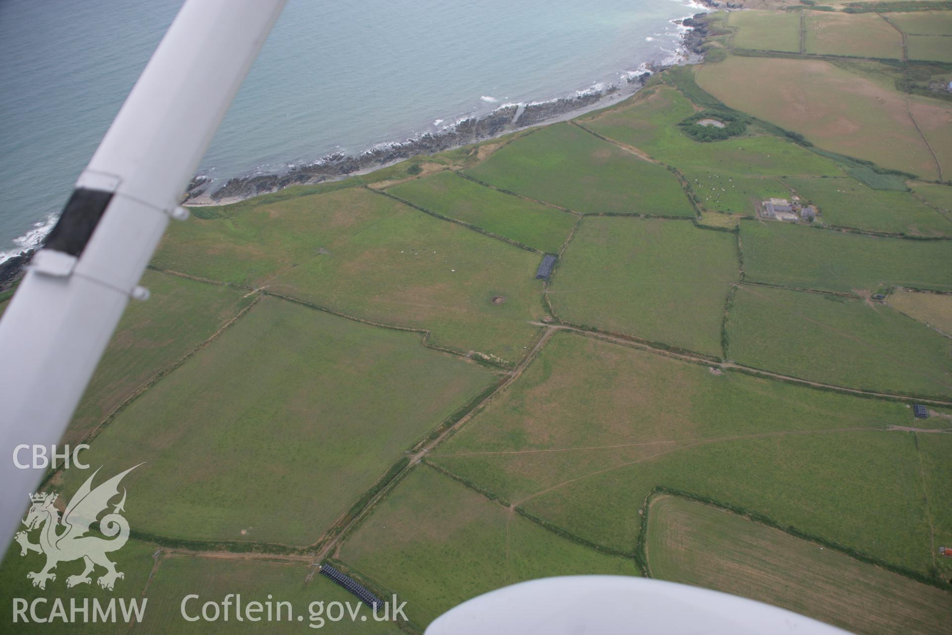 RCAHMW colour oblique aerial photograph of the cropmarks of an enclosure at Cwmistir Uchaf. A wide view from the west. Taken on 03 August 2006 by Toby Driver.