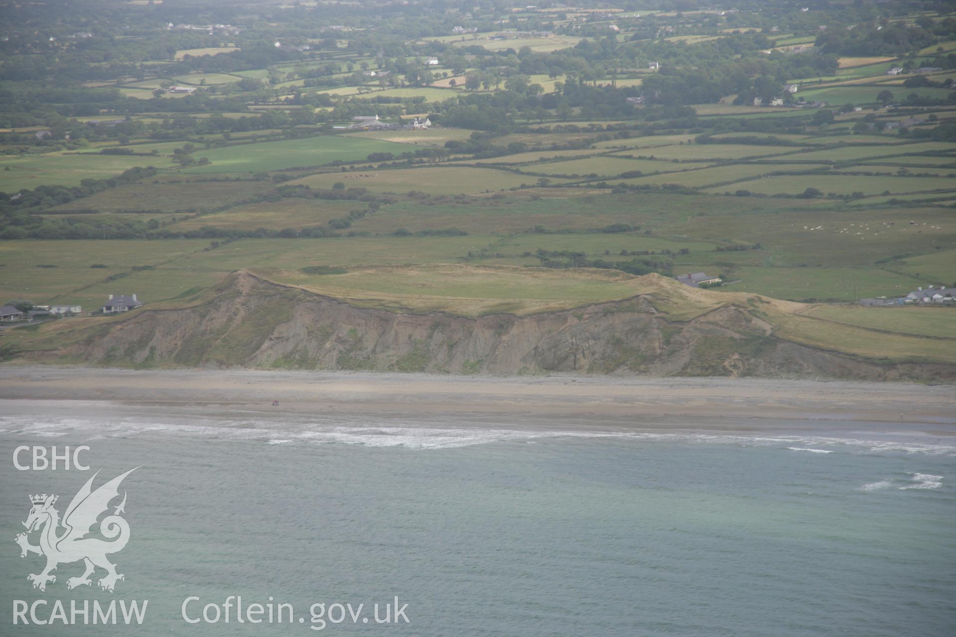 RCAHMW colour oblique aerial photograph of Dinas Dinlle Hillfort, Llandwrog. Viewed from the west showing the fort's 'cross-section' in the cliffs. Taken on 03 August 2006 by Toby Driver.