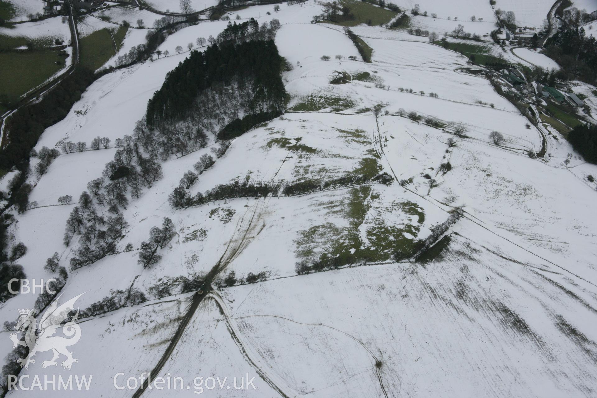 RCAHMW colour oblique aerial photograph of Llwyn Bryn-Dinas hillfort in snow. Taken on 06 March 2006 by Toby Driver