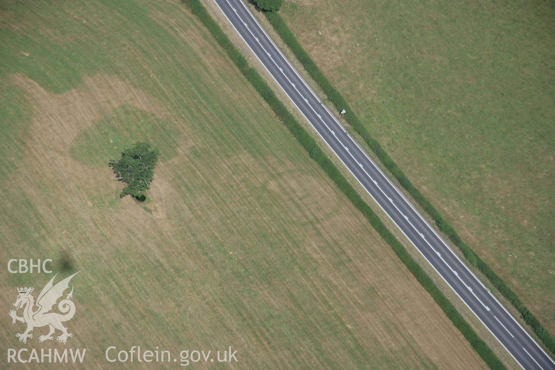 RCAHMW colour oblique aerial photograph of the ring ditch or plough-levelled round barrow at the Moat Farm. Taken on 25 July 2006 by Toby Driver.