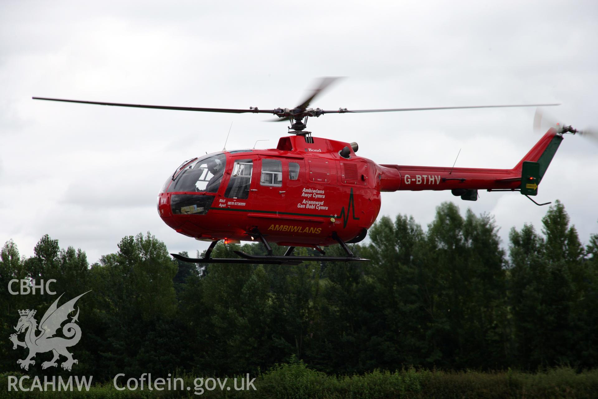 RCAHMW colour oblique aerial photograph of Montgomeryshire Mid Wales Airport, showing air ambulance in flight. Taken on 05 August 2006 by Toby Driver.