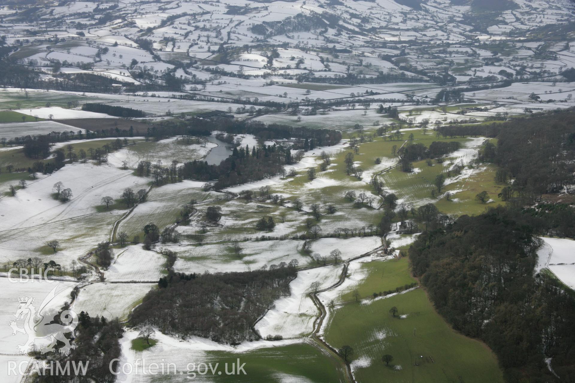 RCAHMW colour oblique aerial photograph of Rug Park from the north-east under melting snow. Taken on 06 March 2006 by Toby Driver.