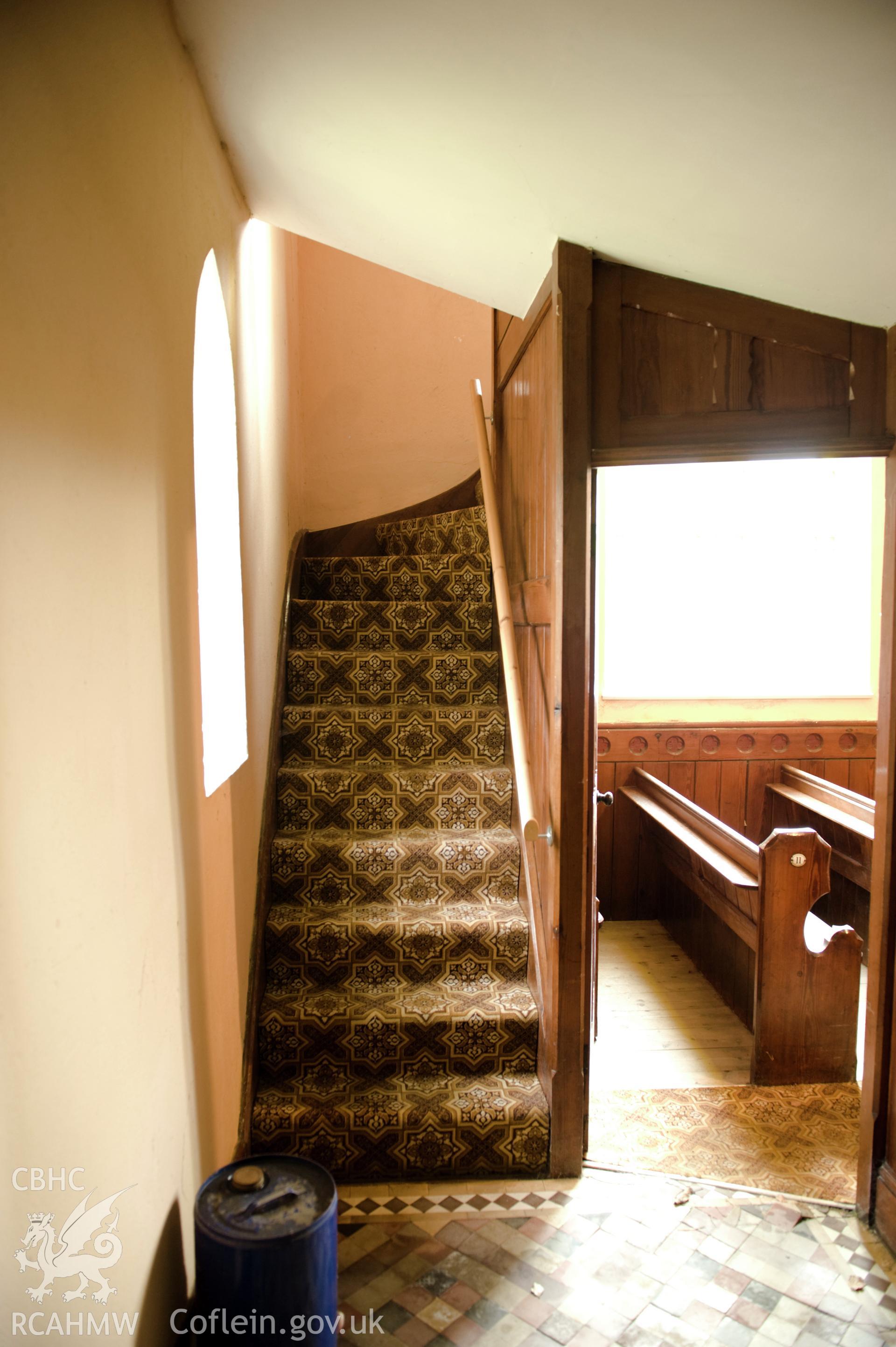 Digital image of interior: showing stairs, and pews through open doorway.