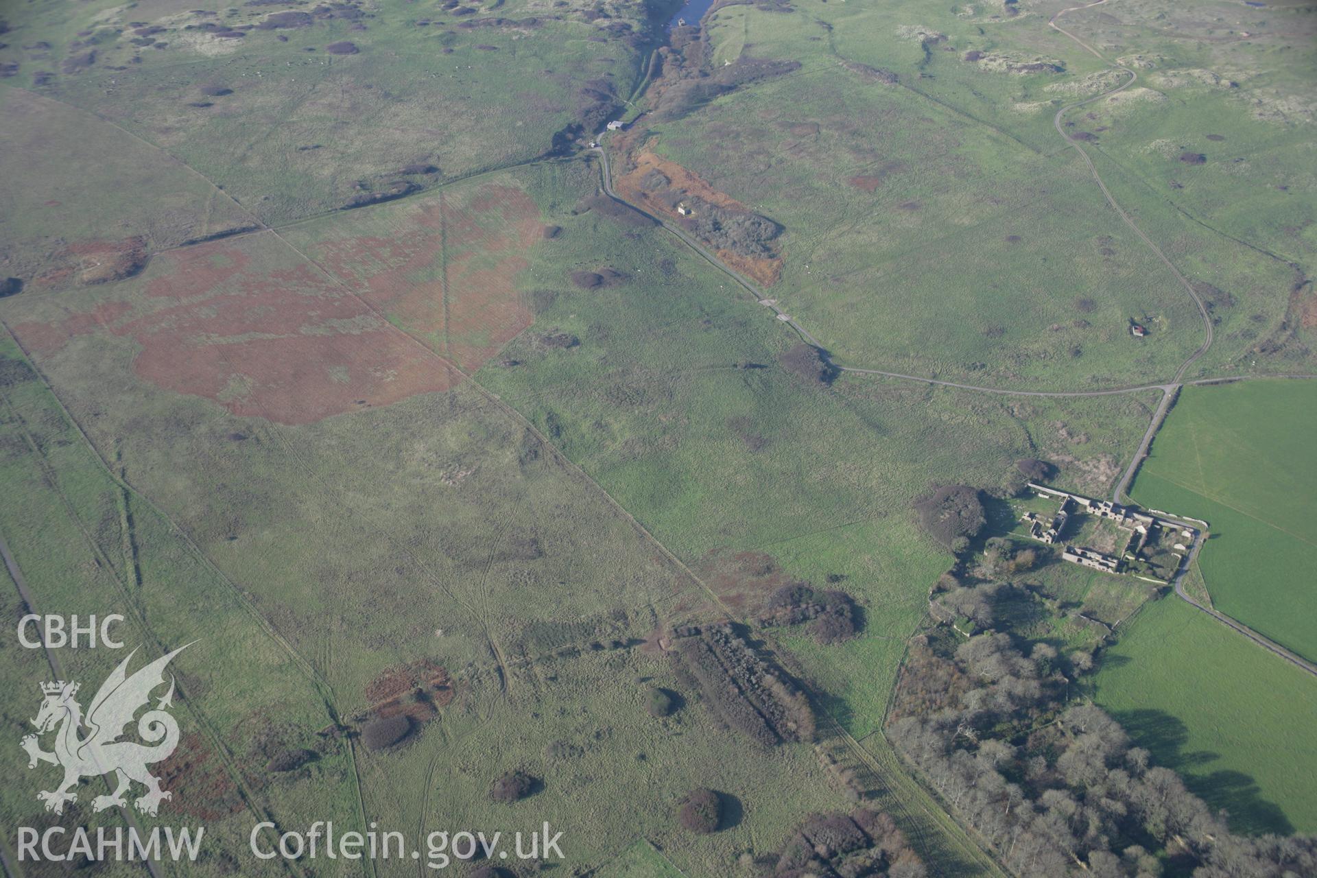 RCAHMW colour oblique aerial photograph of Brownslade Round Barrow, early medieval cemetery, and Brownslade Home Farm, Castlemartin, in general view from the east. Taken on 19 November 2005 by Toby Driver