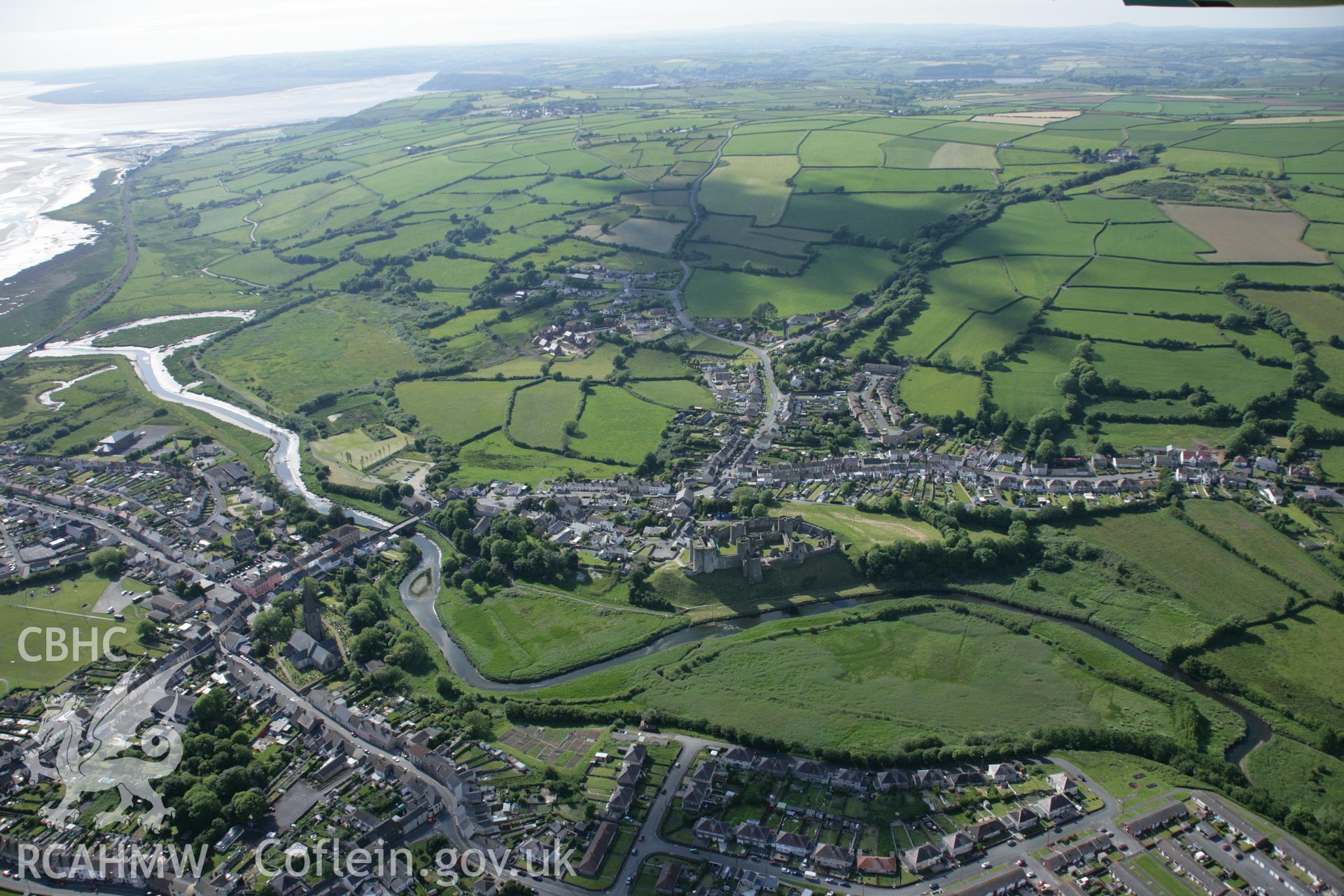 RCAHMW colour oblique aerial photograph of Kidwelly Castle and town, shown with wide view from the east Taken on 09 June 2005 by Toby Driver