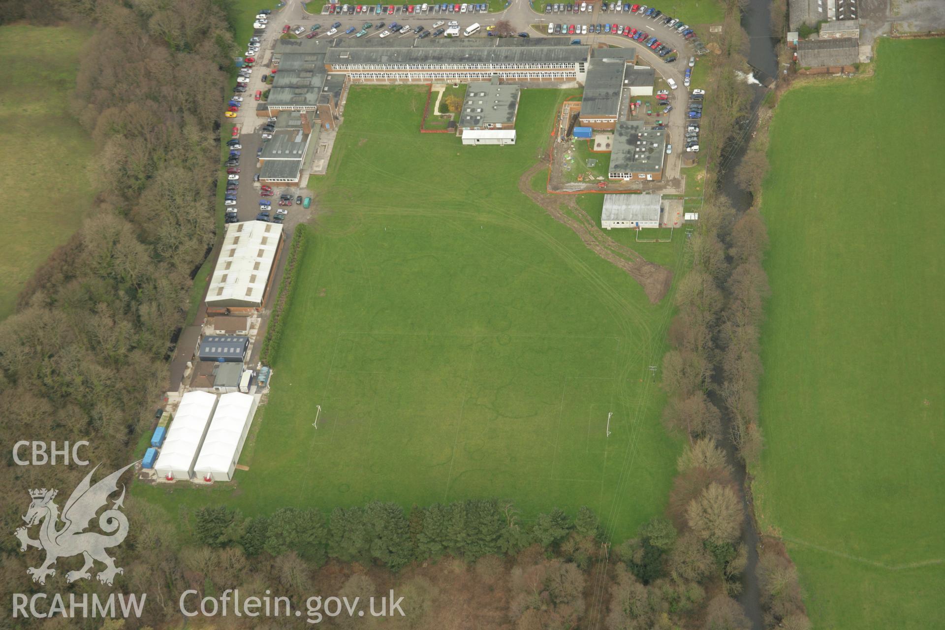 RCAHMW colour oblique aerial photograph of Tir-y-Dail Motte and Bailey, Ammanford, Rhydaman, with fairy rings on the playing fields to the west. Taken on 16 March 2007 by Toby Driver