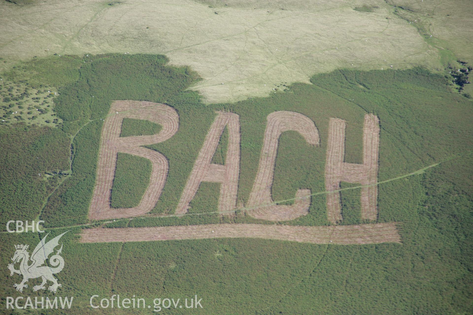RCAHMW colour oblique aerial photograph of hillside protest graffiti by BACH (Builth Against Closing Hospitals), at Builth Wells. Taken on 08 August 2007 by Toby Driver