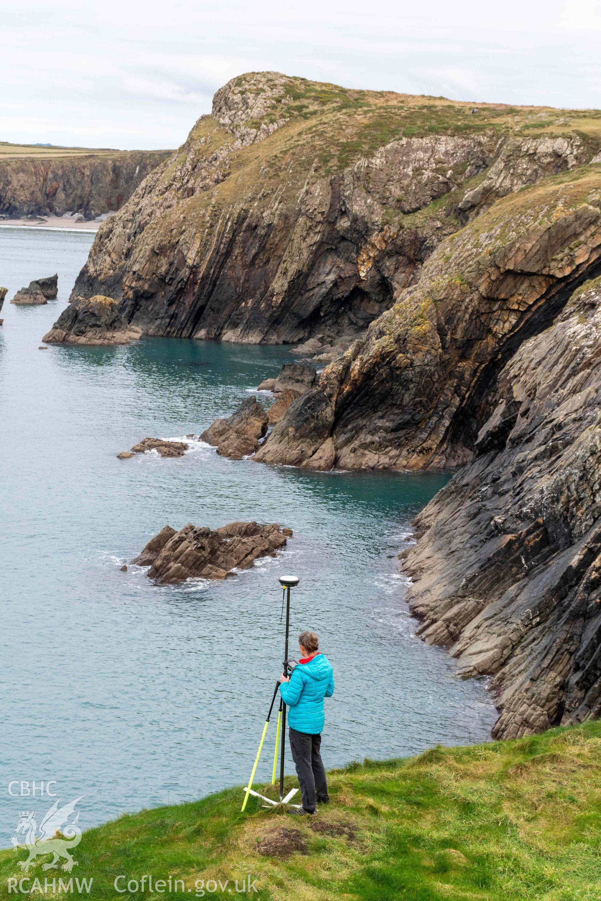 Trwyn Castell coastal promontory fort. RCAHMW investigator undertaking survey at the fort .