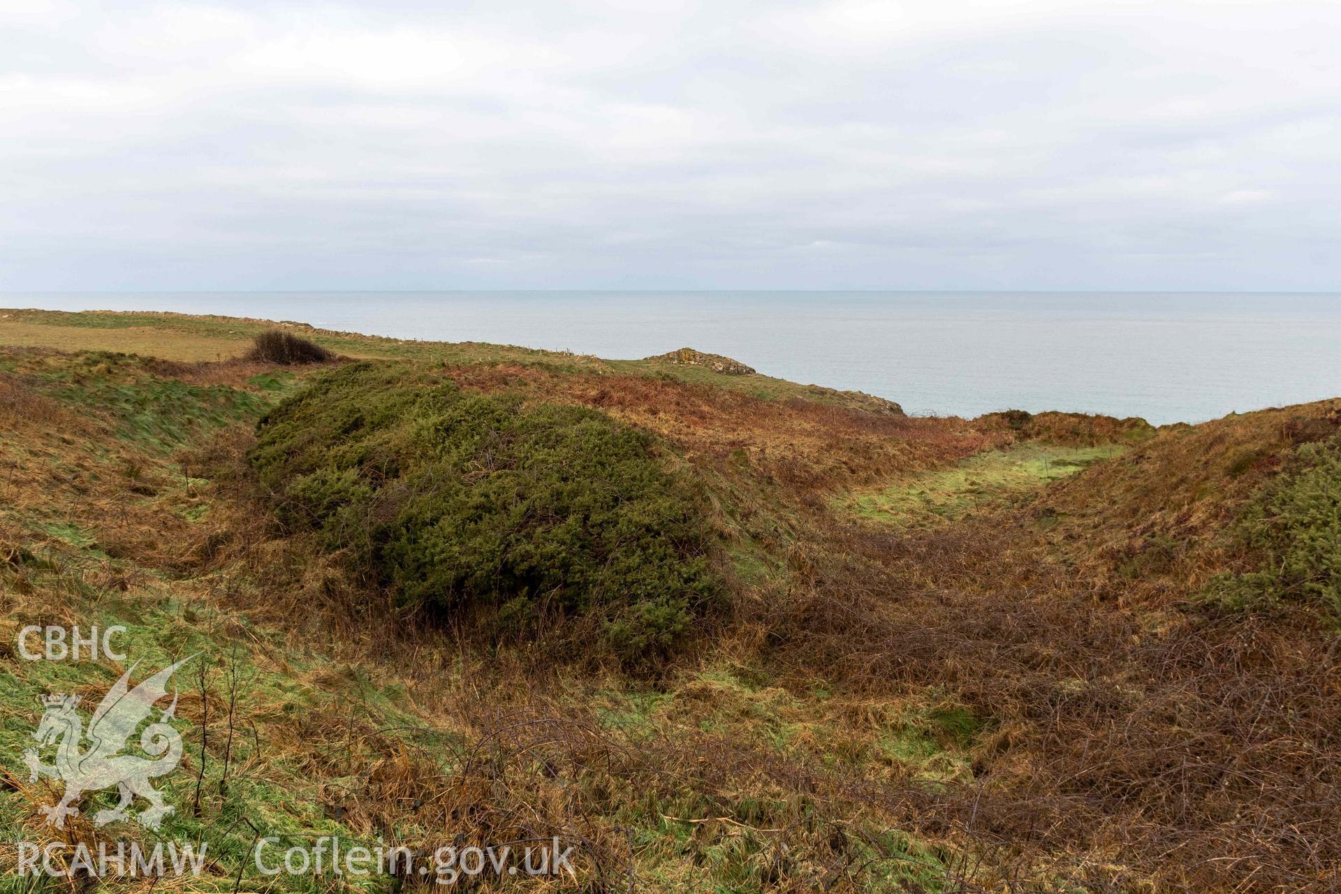 Caer Aber Pwll coastal promontory fort. Looking north along ditch cutting through the middle defence bank on the western side of the fort (with human scale).