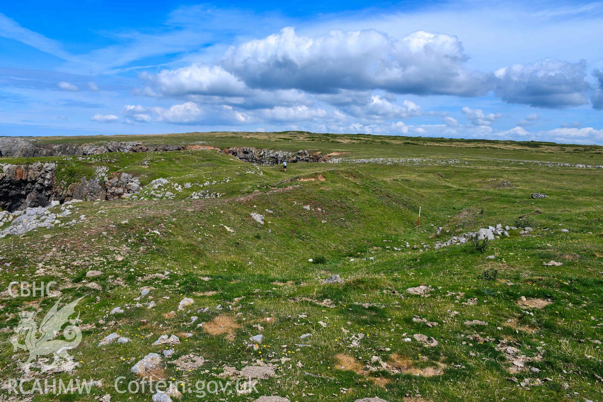 Looking north along the middle rampart bank and ditch to the south of the fort gateway (with scale).