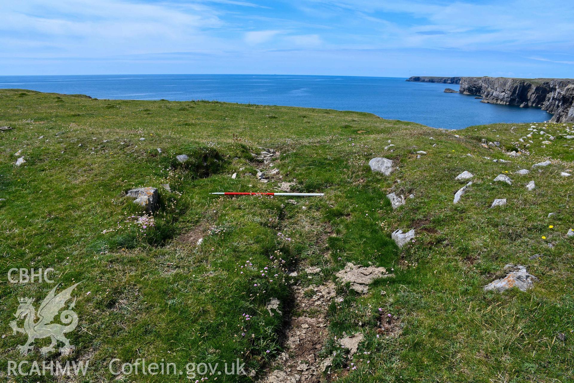 Footpath cutting into the inner rampart bank with possible exposed stonework (with scale)