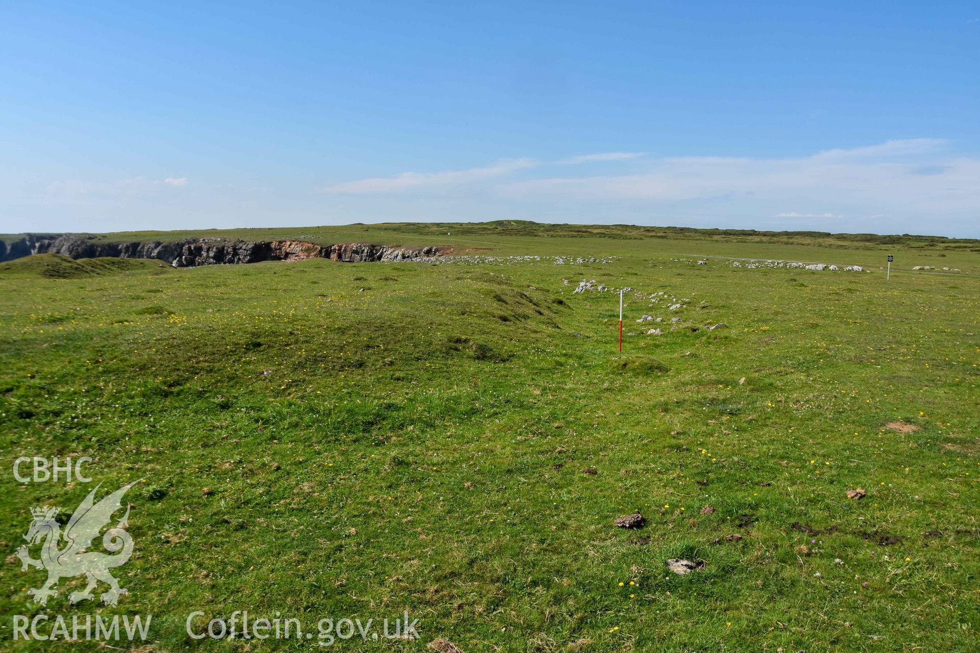 Looking northwest along the outer rock-cut ditch from the southern end where it curves west to the define the appraoch to the entrance (with scale).