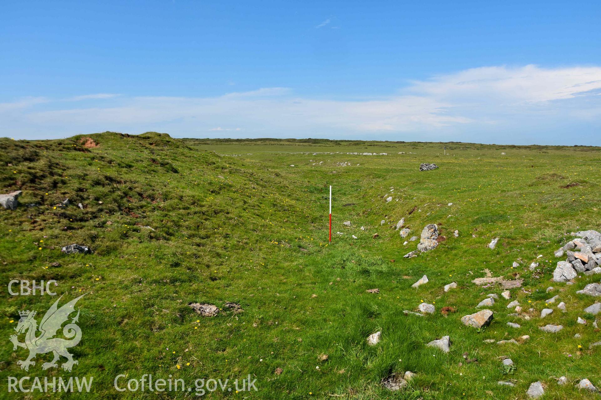 Looking north along the ditch and bank of the middle rampart to the south of fort gateway. Part of the ditch has been recut and faced in recent times (with scale).