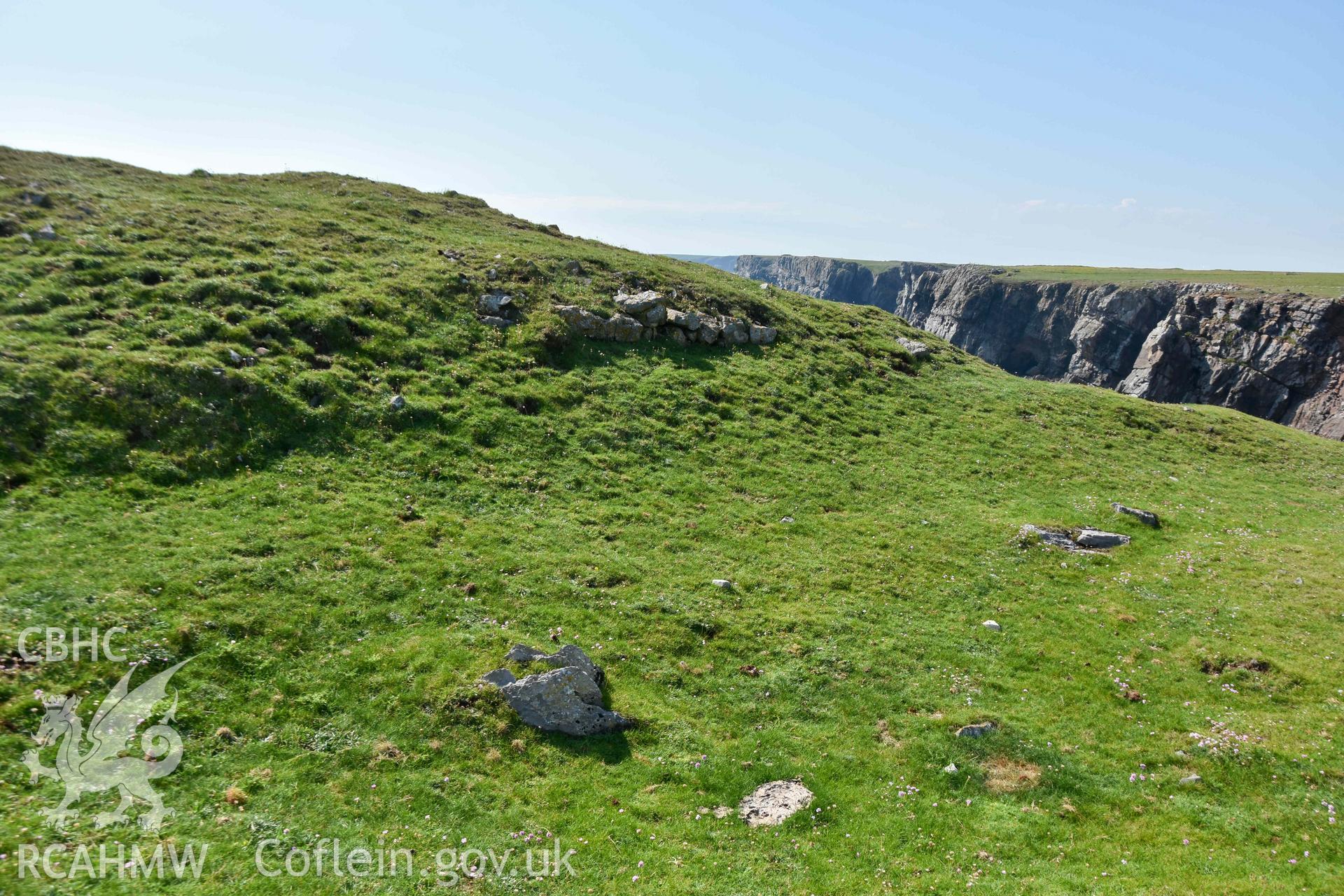 Exposed limestone block walling defining the outer face of the inner rampart bank.