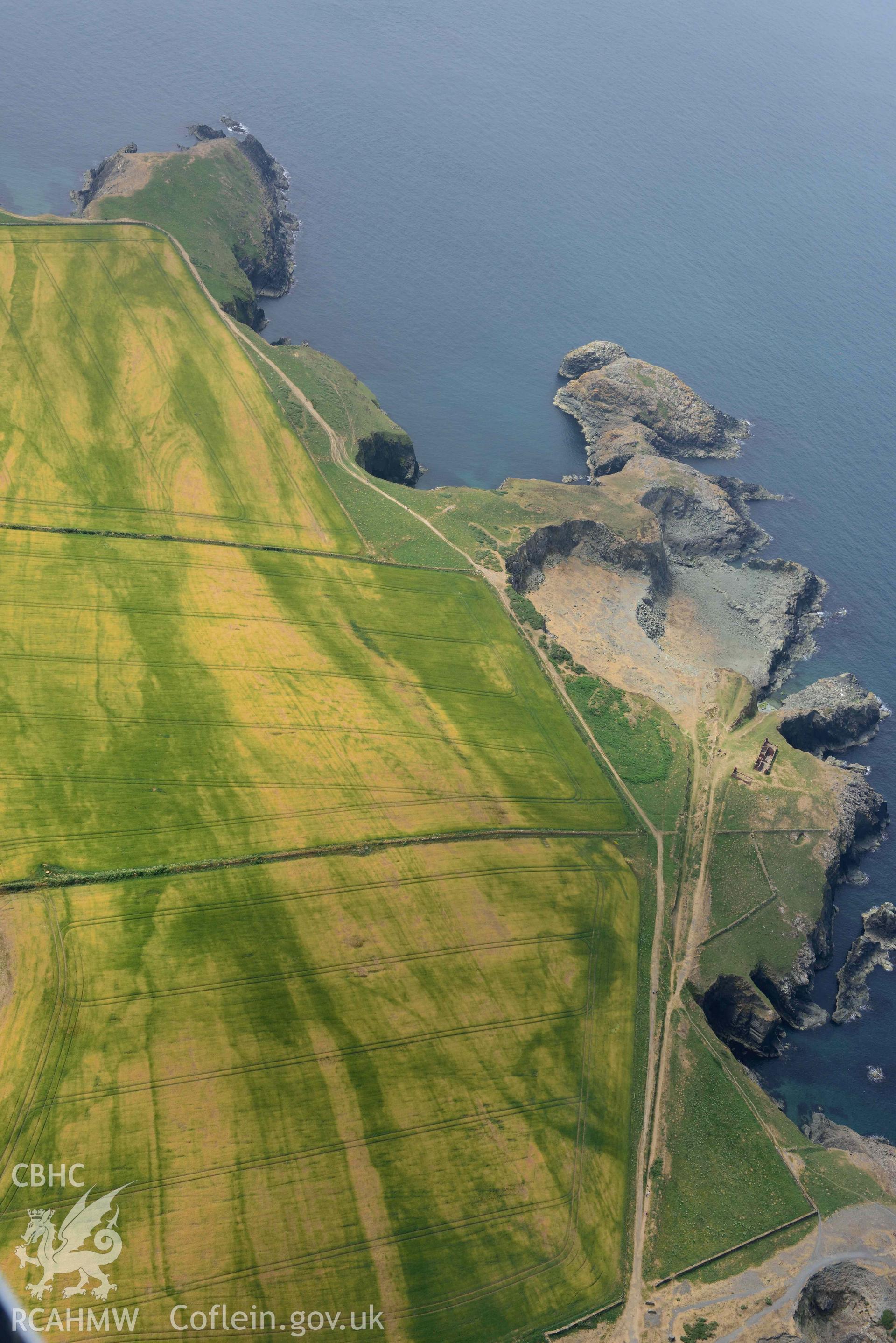 RCAHMW colour oblique aerial photograph of Porthgain quarries and geological cropmarks taken on 11 July 2018 by Toby Driver