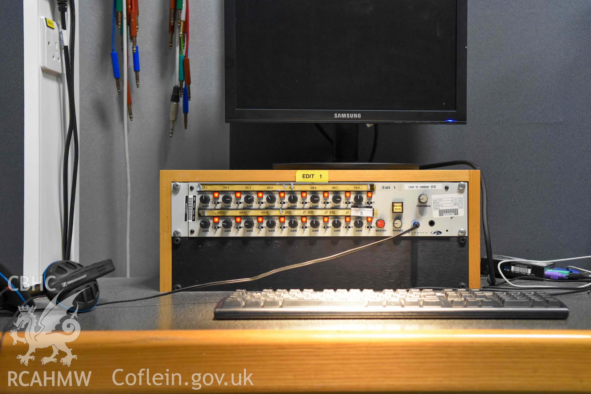 BBC Broadcasting House - Interior, R6 Cubicle: Detailed view of a portion of a monitor and audio mixing equipment, taken from West