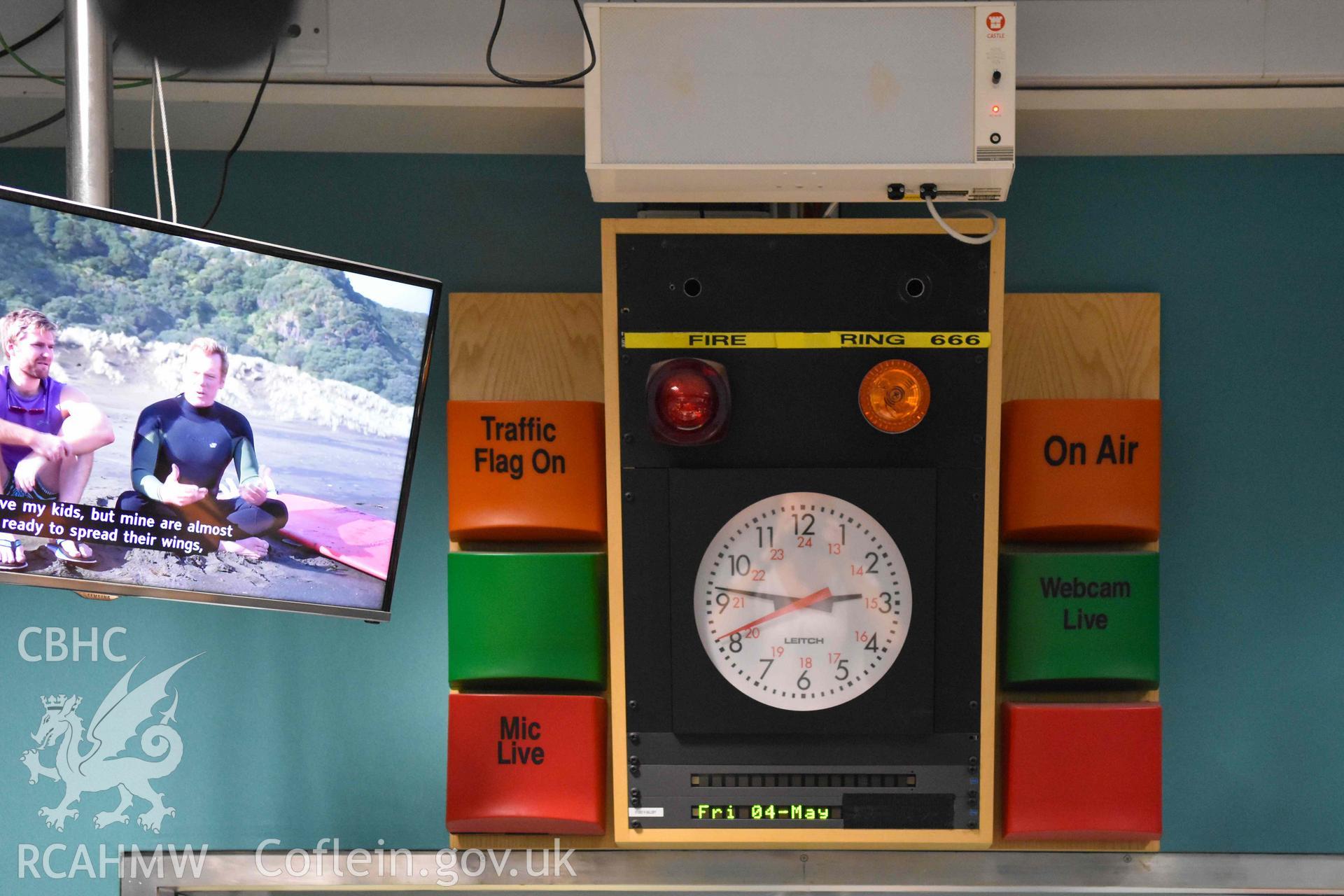BBC Broadcasting House - Interior, R6 Cubicle: Detailed view of the studio clock and a portion of a ceiling mounted monitor, taken from North
