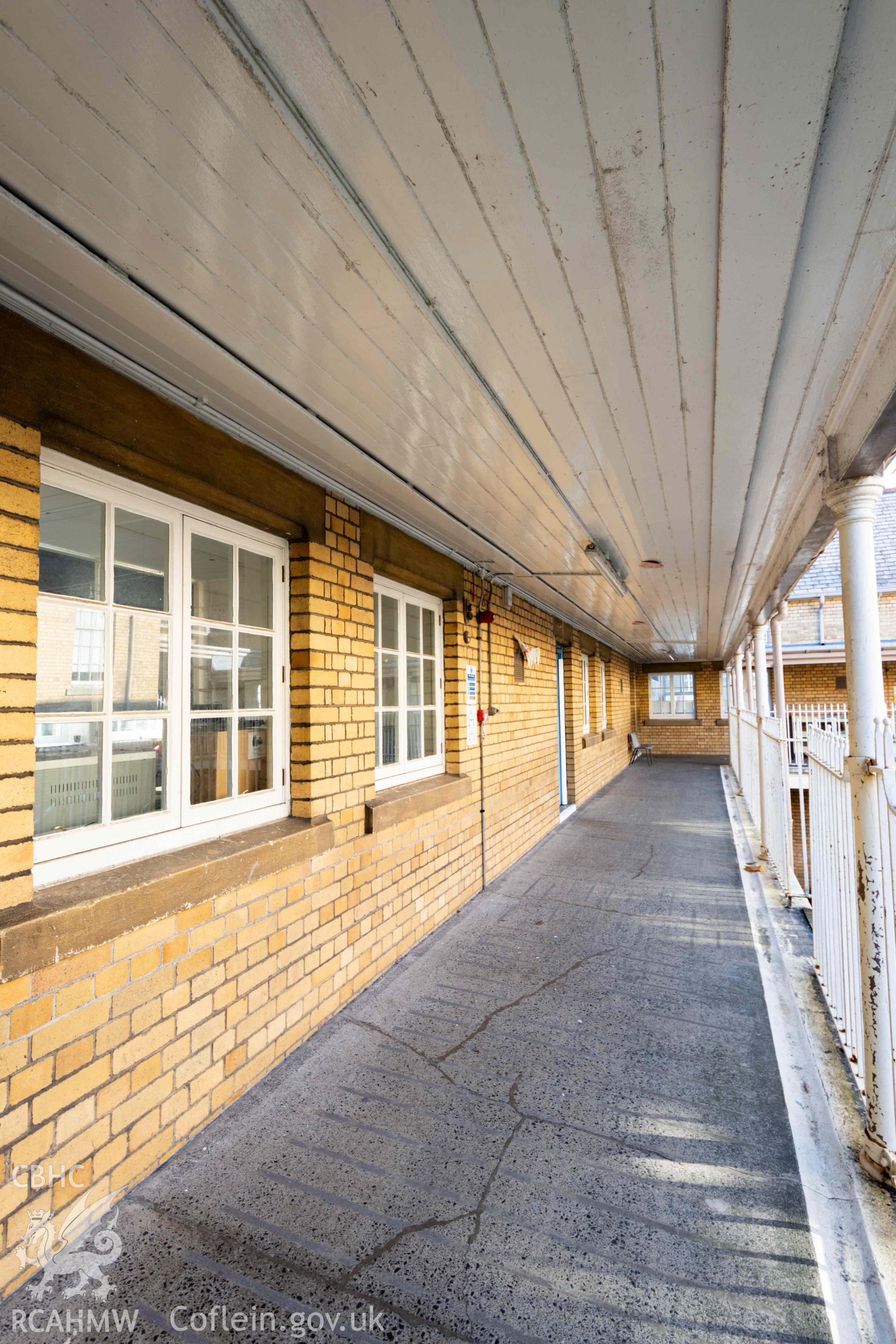 View along first floor walkway, south wing. Windows to classrooms on left