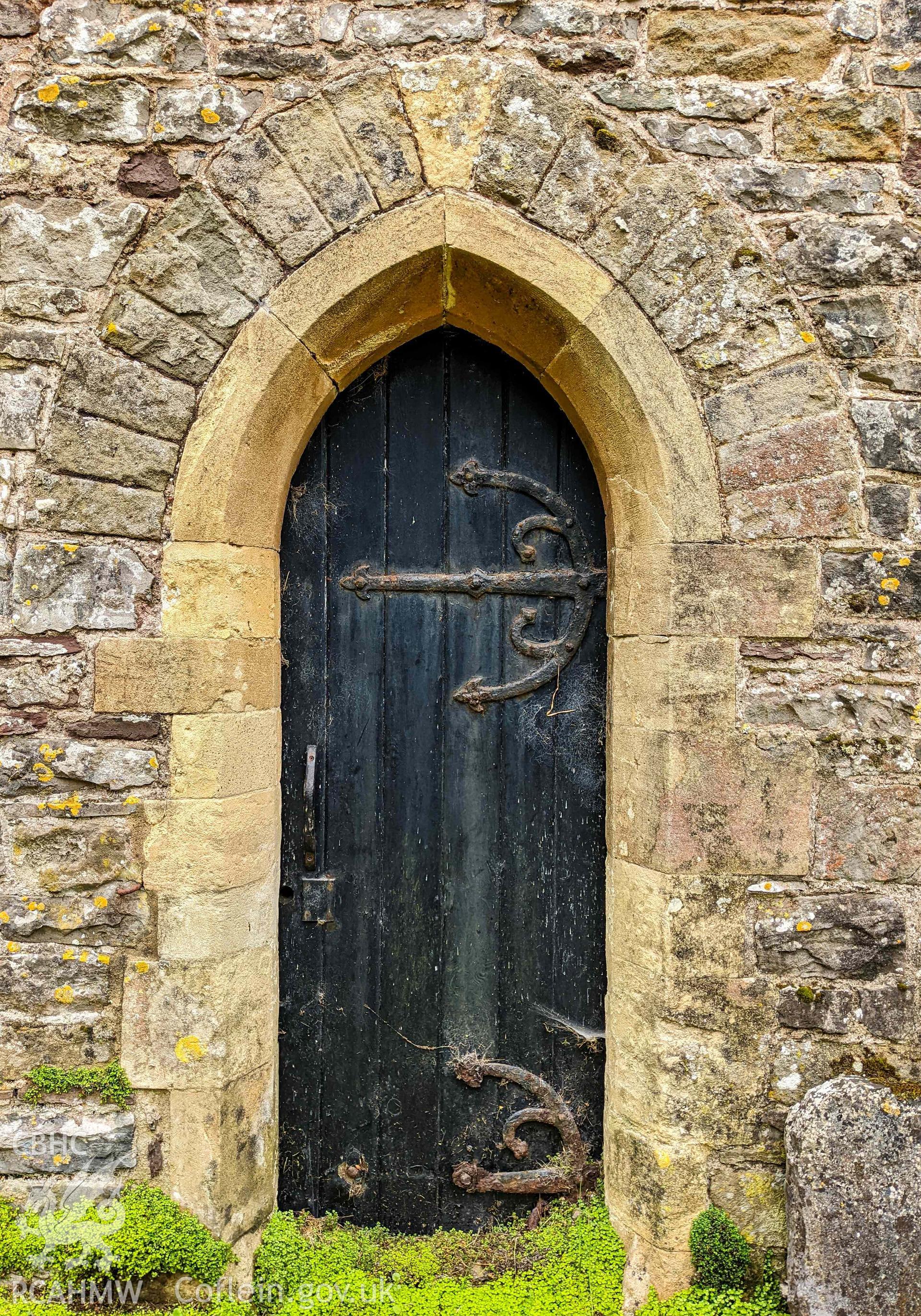 Narrow black painted wooden door with gothic arch surround