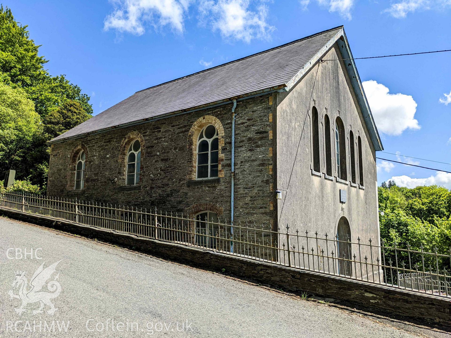 Front (west) and side (north) elevations, taken from across the road. Railings and low stone wall in foreground. Looling south east